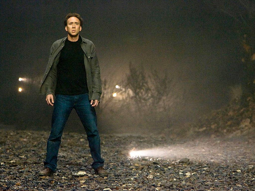 尼可拉斯·凱吉 桌布 壁紙 — 一個男人獨自站在夜晚的碎石路上，車頭燈從他身後穿透霧氣。