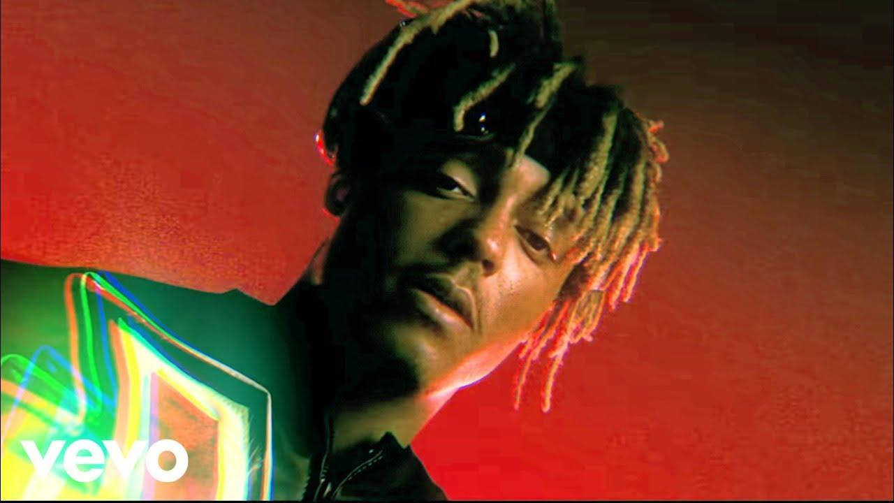 Juice Wrld Desktop 桌布 壁紙 — 一個男人留著辮子頭，在充滿活力的紅色背景上帶有霓虹綠色燈光效果的近距離肖像。