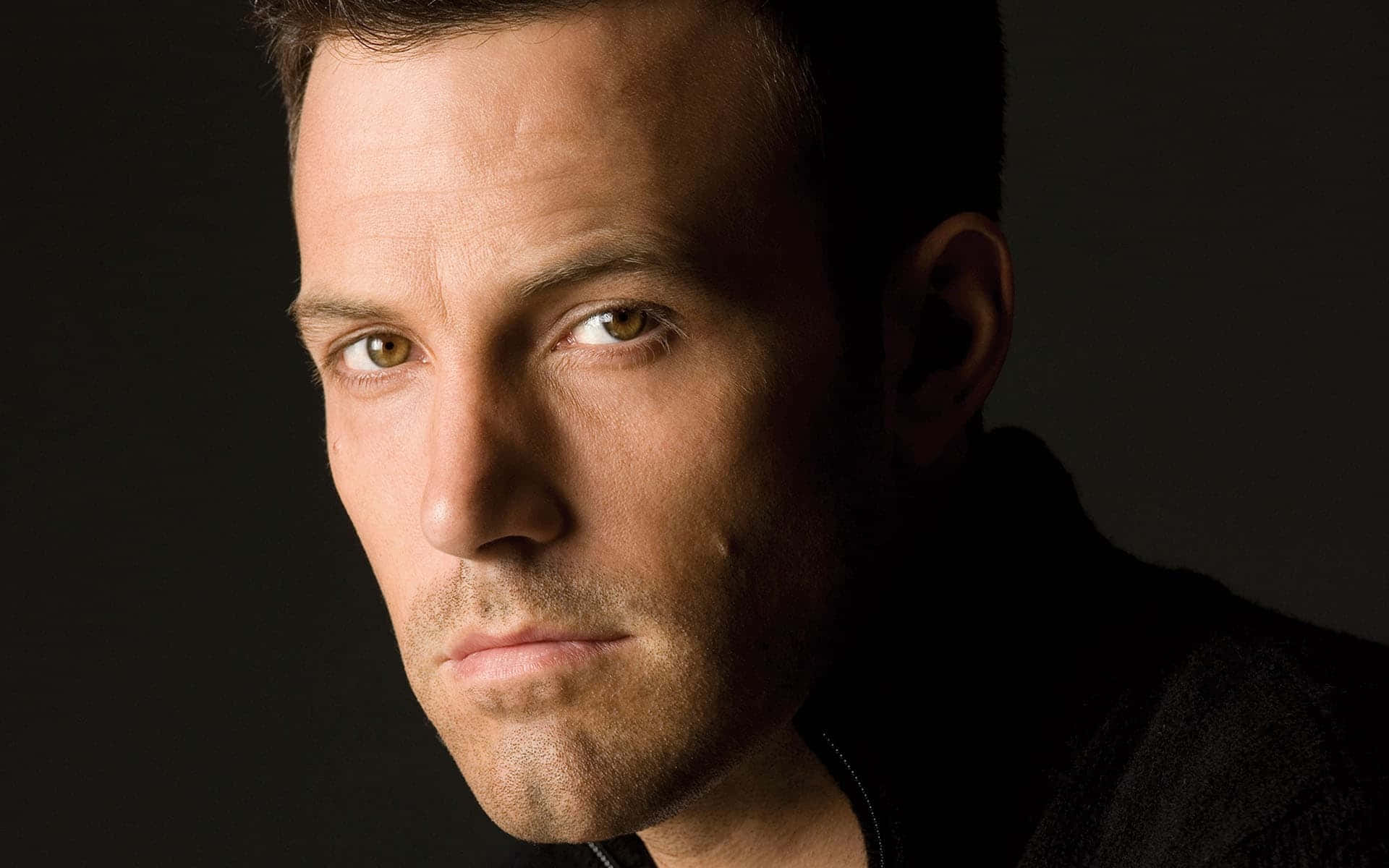 Ben Affleck 桌布 壁紙 — 一個男人的特寫肖像，在黑暗背景下帶有強烈的眼神。