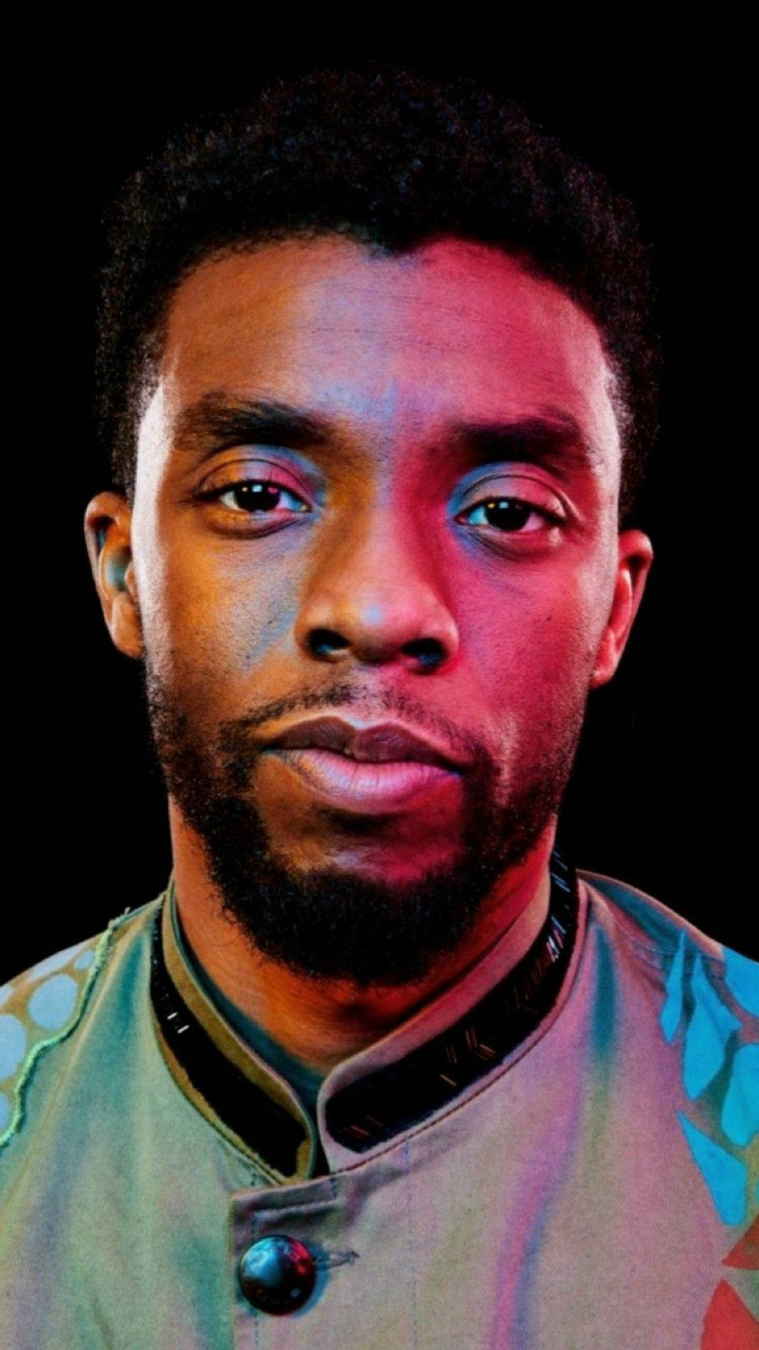 Chadwick 桌布 壁紙 — 一個男人的特寫肖像，在黑色背景上的戲劇性紅色和藍色燈光下帶有嚴肅表情。