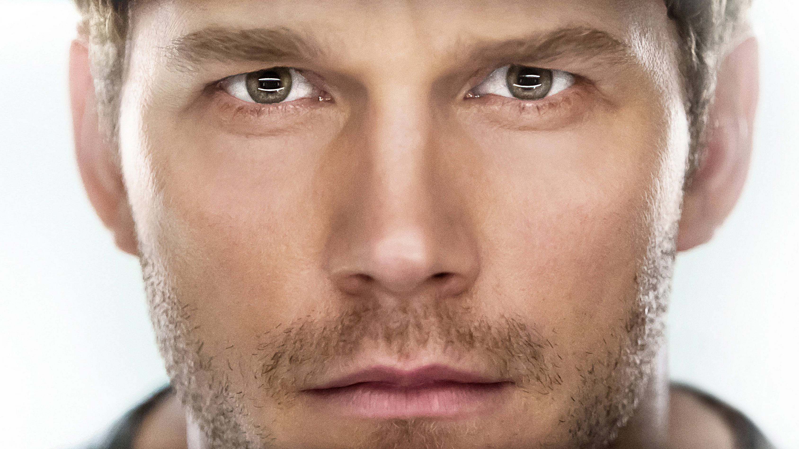 Chris Pratt 桌布 壁紙 — 一個男人的特寫肖像，擁有強烈的棕色眼睛和鬍渣，背景是柔和的白色。