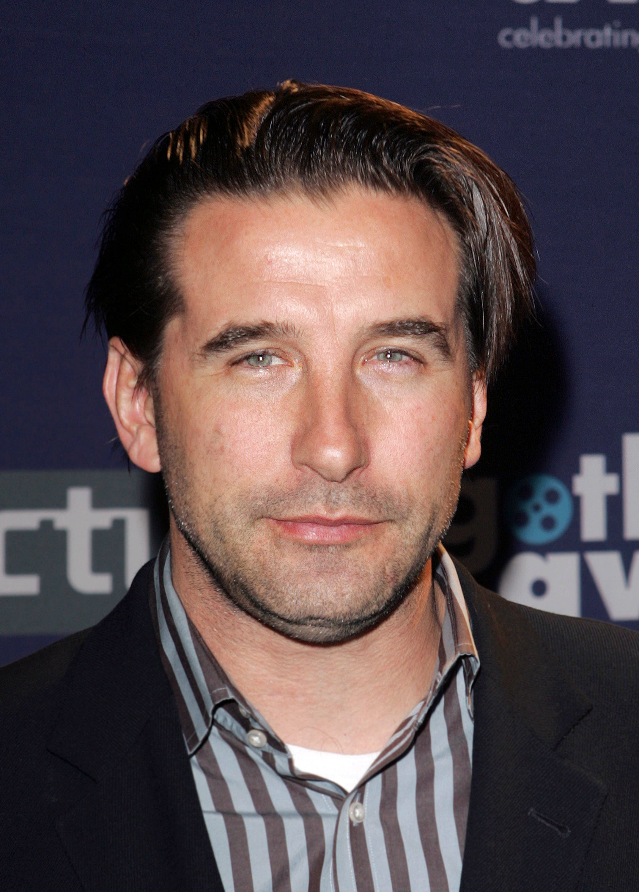 William Baldwin 桌布 壁紙 — 一個男人的特寫肖像，頭髮向後梳，穿著條紋襯衫，背景是深藍色的活動背景。