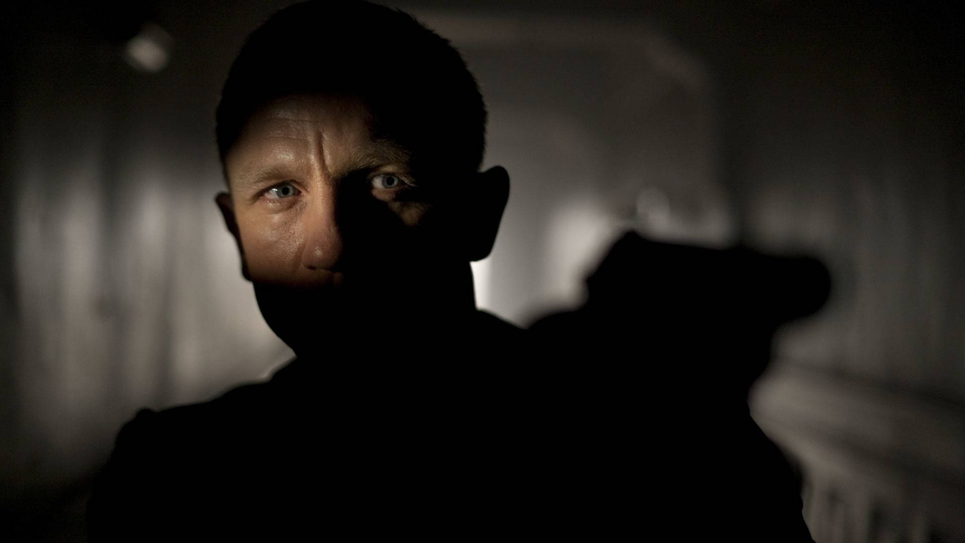 Daniel Craig 桌布 壁紙 — 一個男人的臉半邊在陰影中，眼神銳利，在光線昏暗的走廊中直視前方。