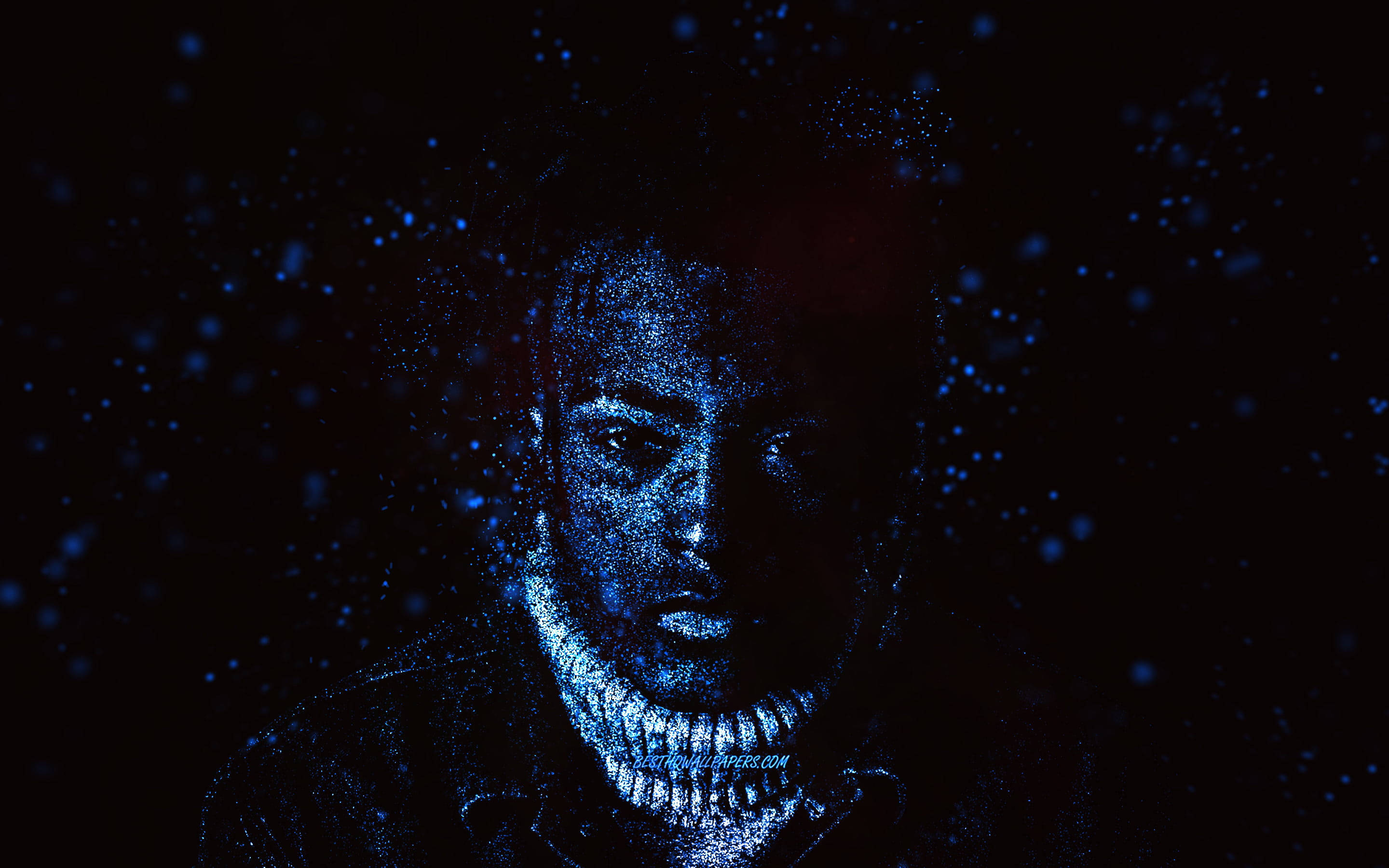 xxxtentacion 電腦 桌布 壁紙 — 一個男人的臉從黑暗中浮現，發光的藍色粒子像宇宙塵埃一樣在他周圍旋轉。