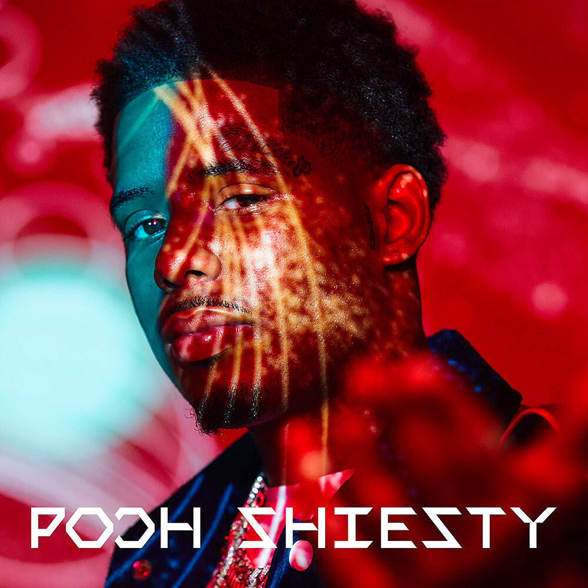 Pooh Shiesty 桌布 壁紙 — 一個男人的臉被鮮豔的紅色和藍綠色光線分割，皮膚上有金色條紋，背景是模糊的彩色。