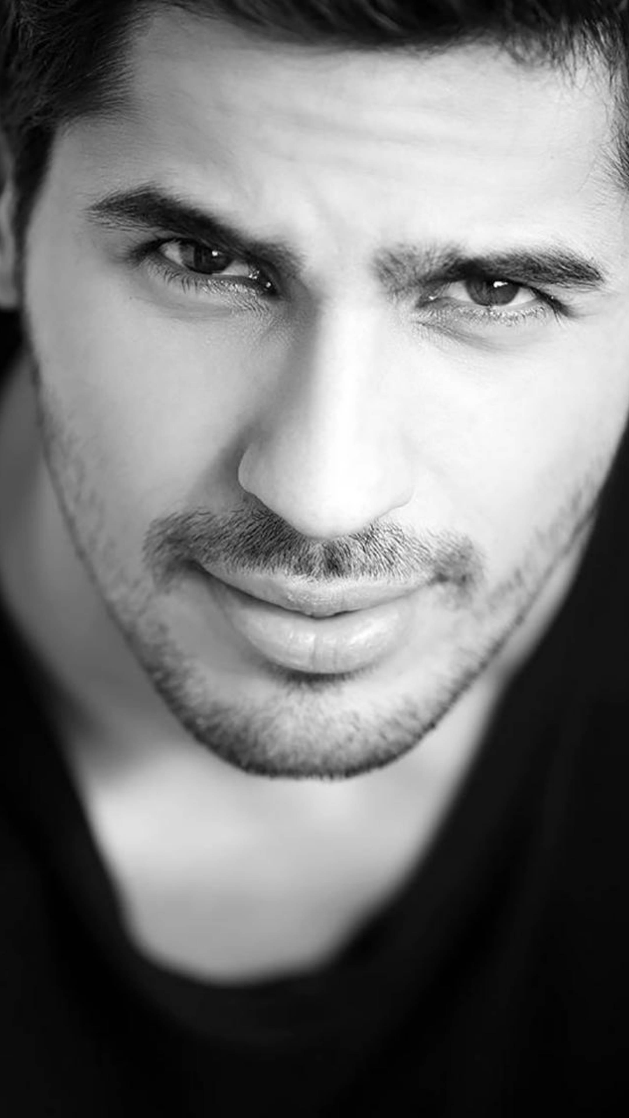 Sidharth Malhotra 桌布 壁紙 — 一個男人的黑白特寫肖像，眼神強烈，帶有微妙的微笑。