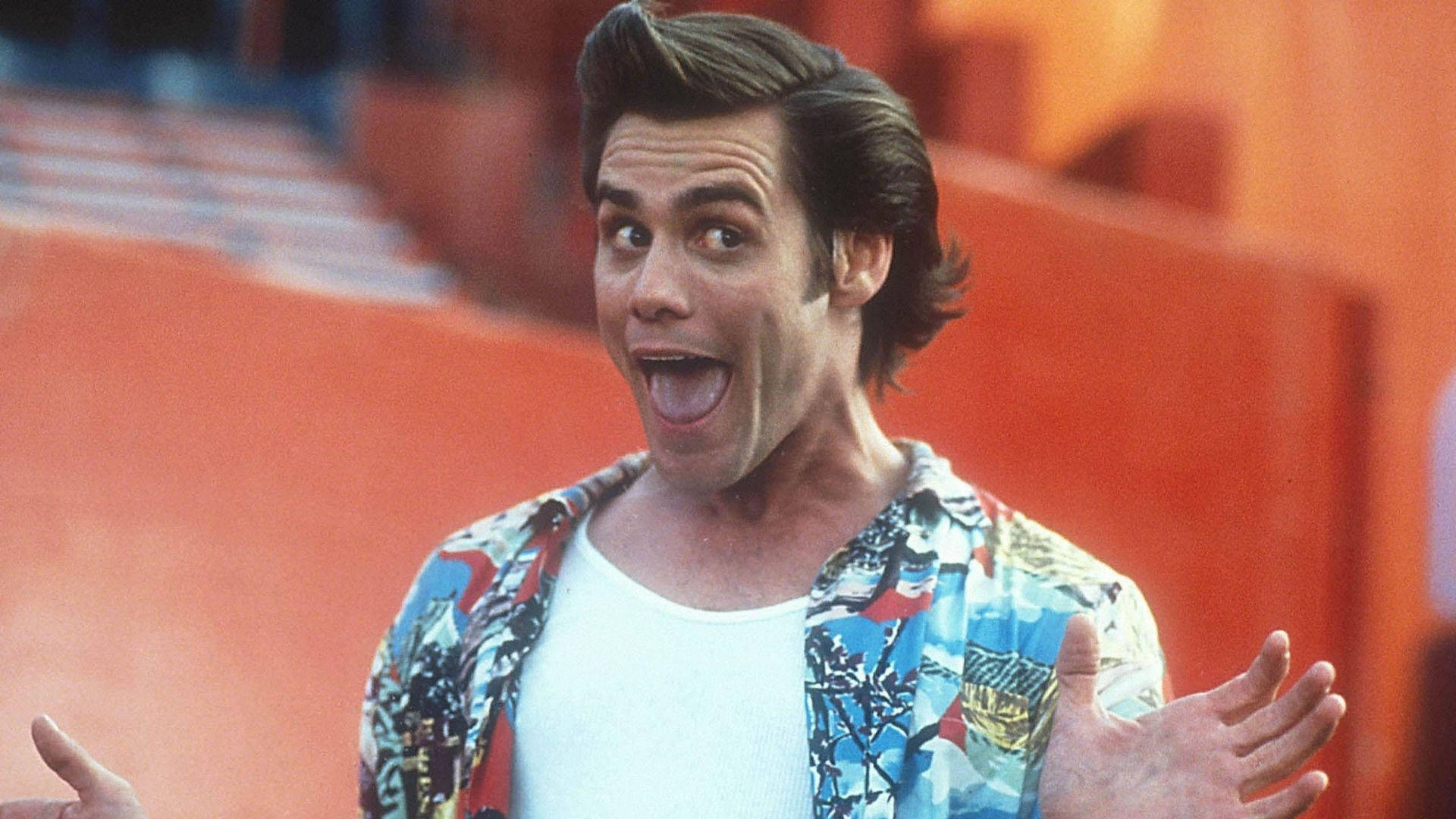 Jim Carrey 桌布 壁紙 — 一個男人睜大眼睛、張開嘴巴，在橙色體育場座位前興奮地做手勢。
