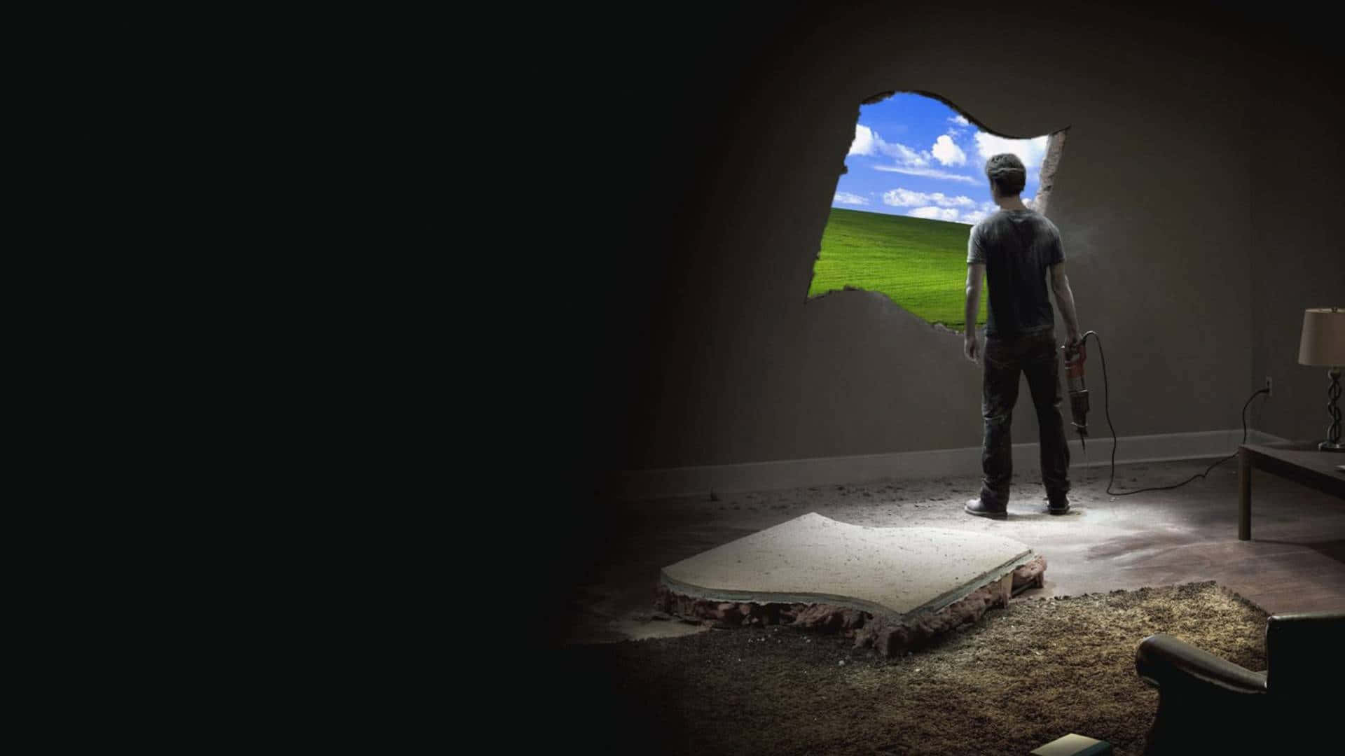 Windows XP 桌布 壁紙 — 一個男人站在黑暗的房間裡，拿著拆除工具，透過牆上的洞看著藍天下明亮的綠色田野。