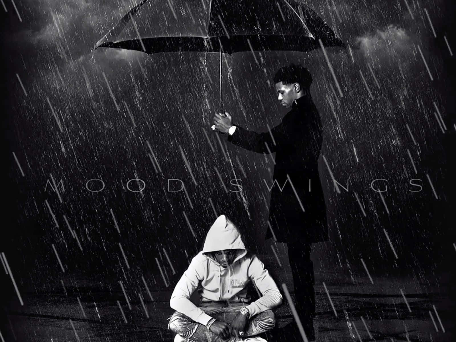Rappers 桌布 壁紙 — 一個男人站著，在黑暗的天空下的大雨中，用雨傘遮住另一個蹲著的人。
