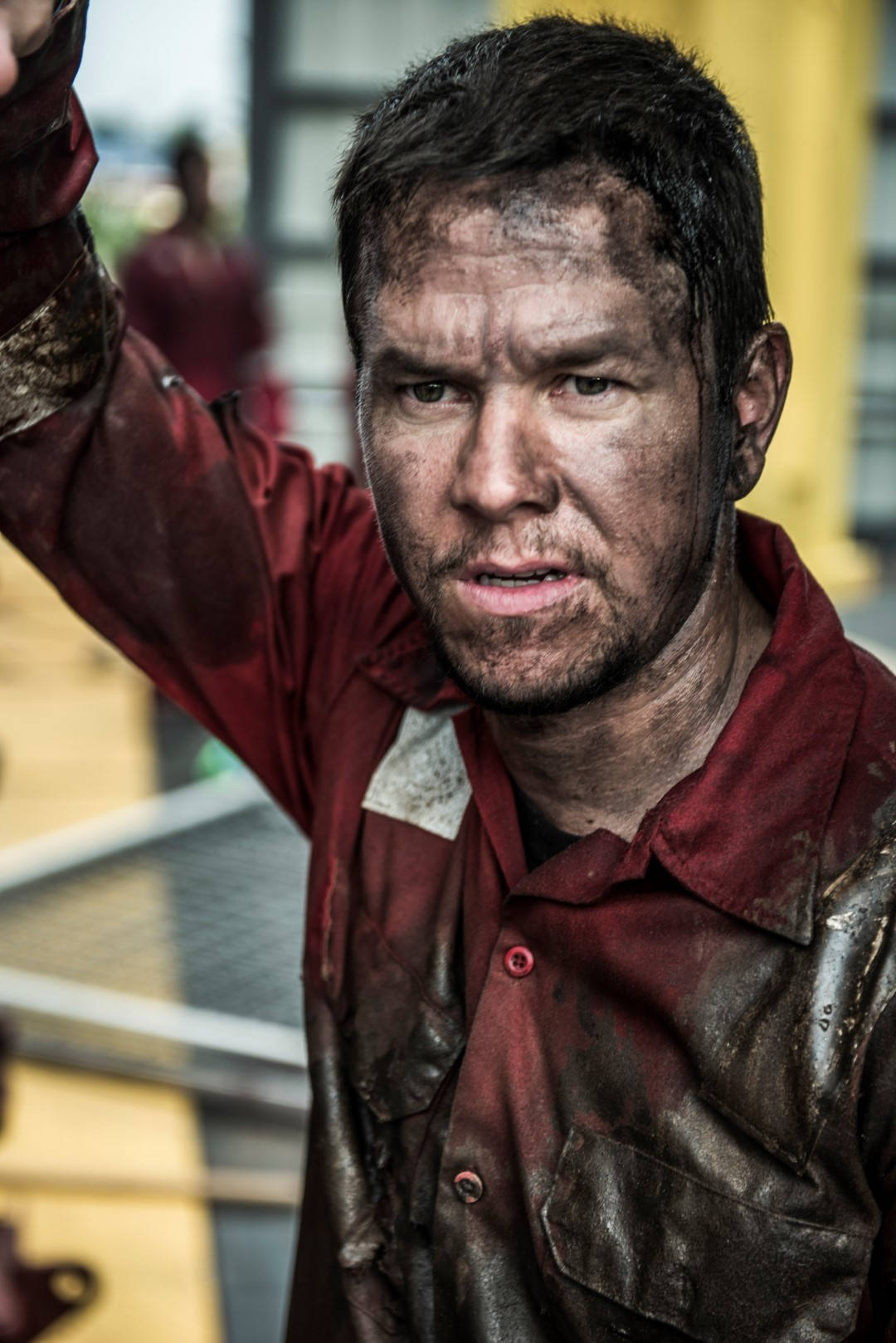 Mark Wahlberg 桌布 壁紙 — 一個男人臉上沾滿污垢和灰塵，身穿紅色污漬襯衫，堅定地舉起手臂的粗獷特寫。