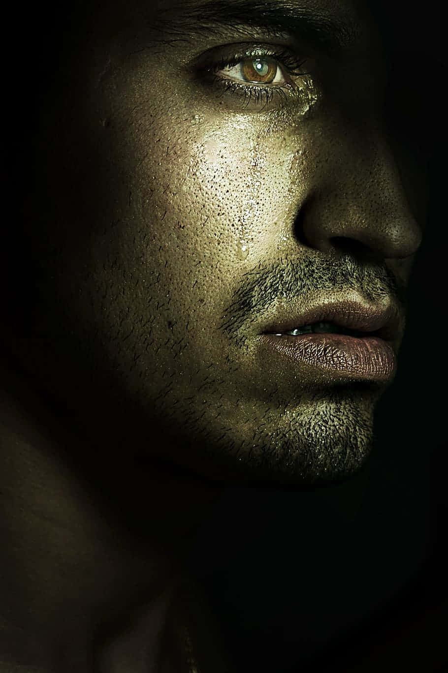 Alone 桌布 壁紙 — 一個男人臉部在陰影中的戲劇性特寫，金色光線突顯汗水與鬍渣。