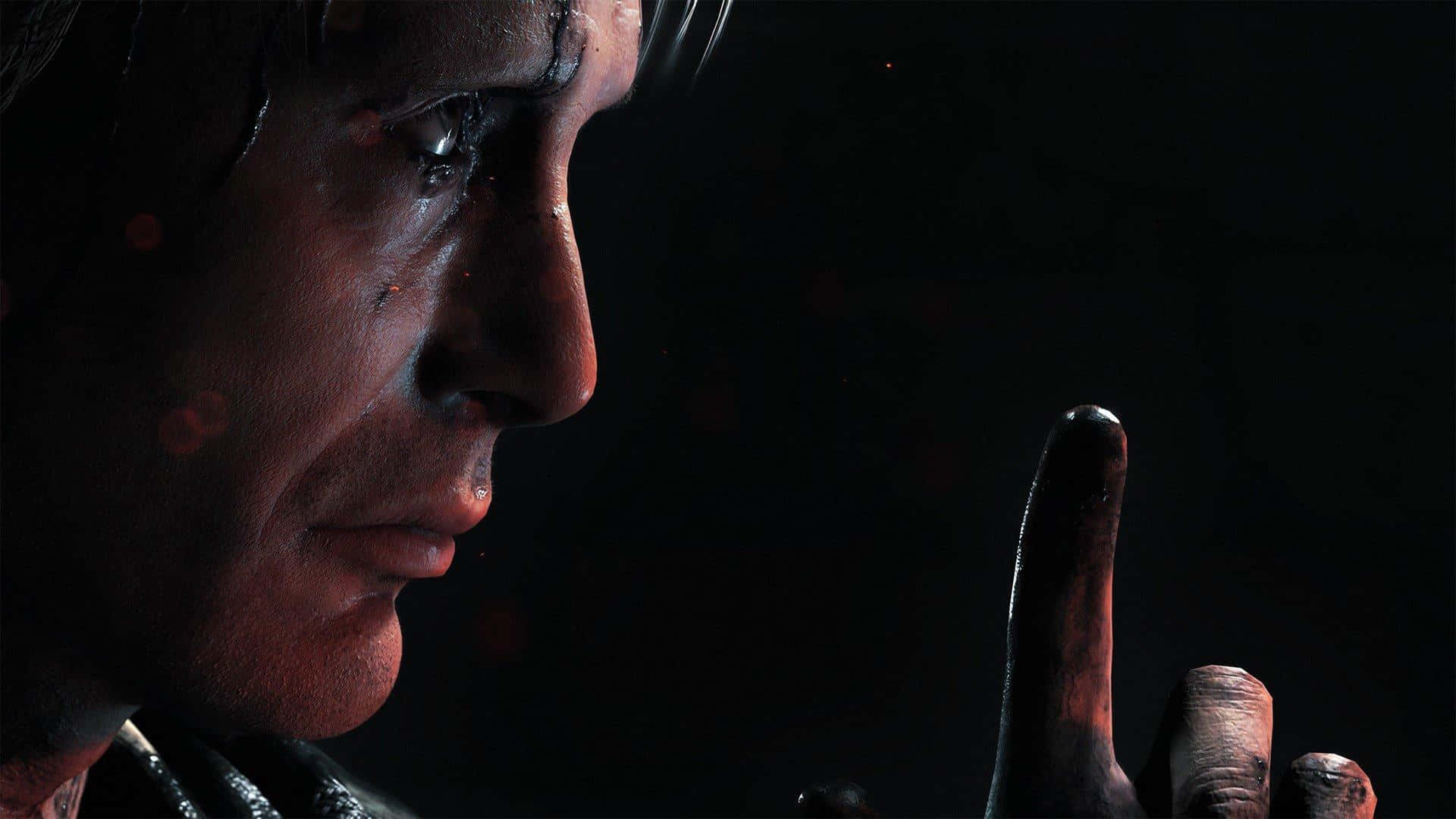 Death Stranding Pc 桌布 壁紙 — 一個男人臉部的特寫，處於陰影中，帶有血痕，並舉起一根手指，背景為深色。