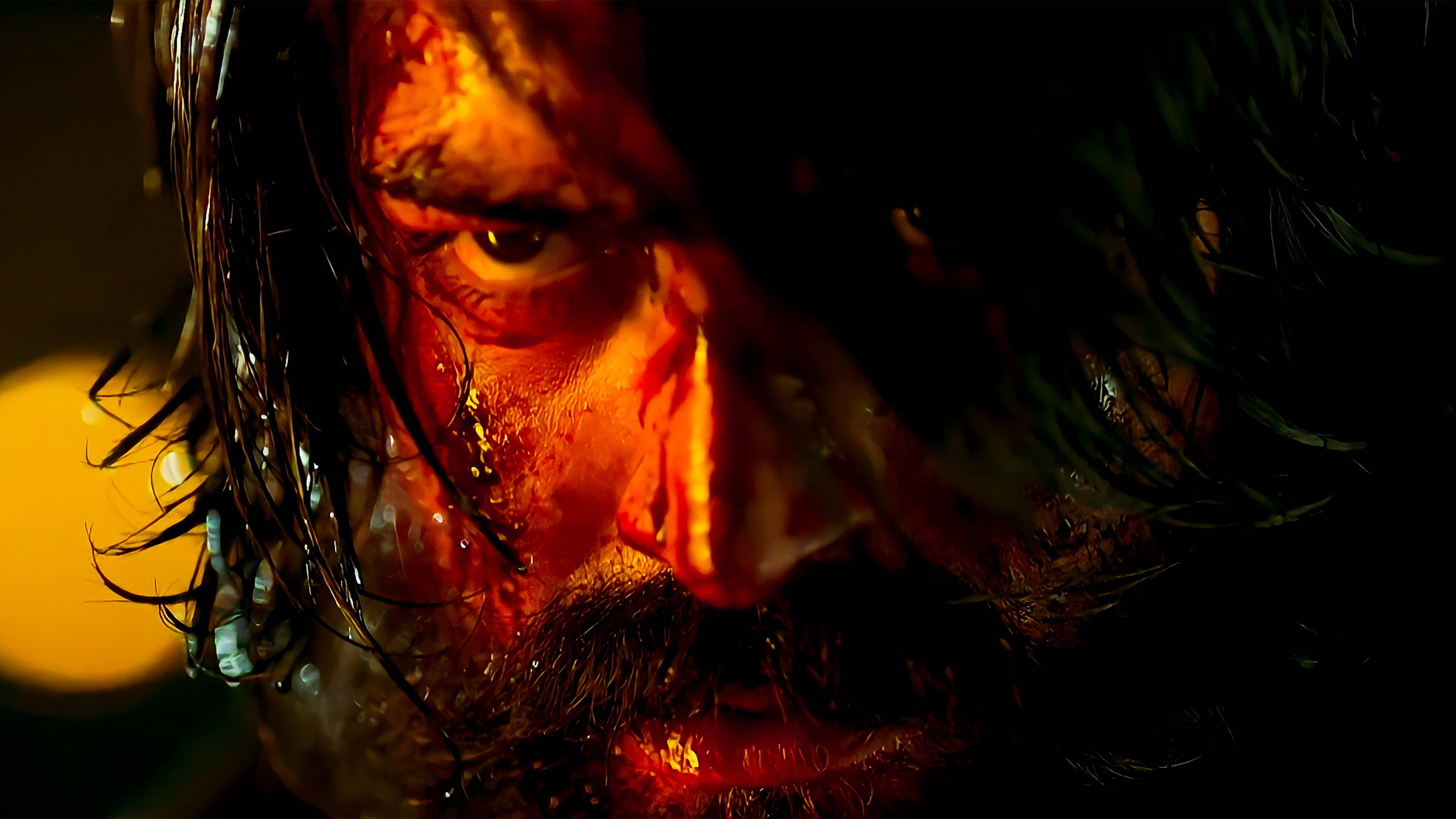 kgf 4K 桌布 壁紙 — 一個男人臉部的特寫，被火熱的橙色光照亮，血沿著臉頰滴下，濕髮貼在額頭上。