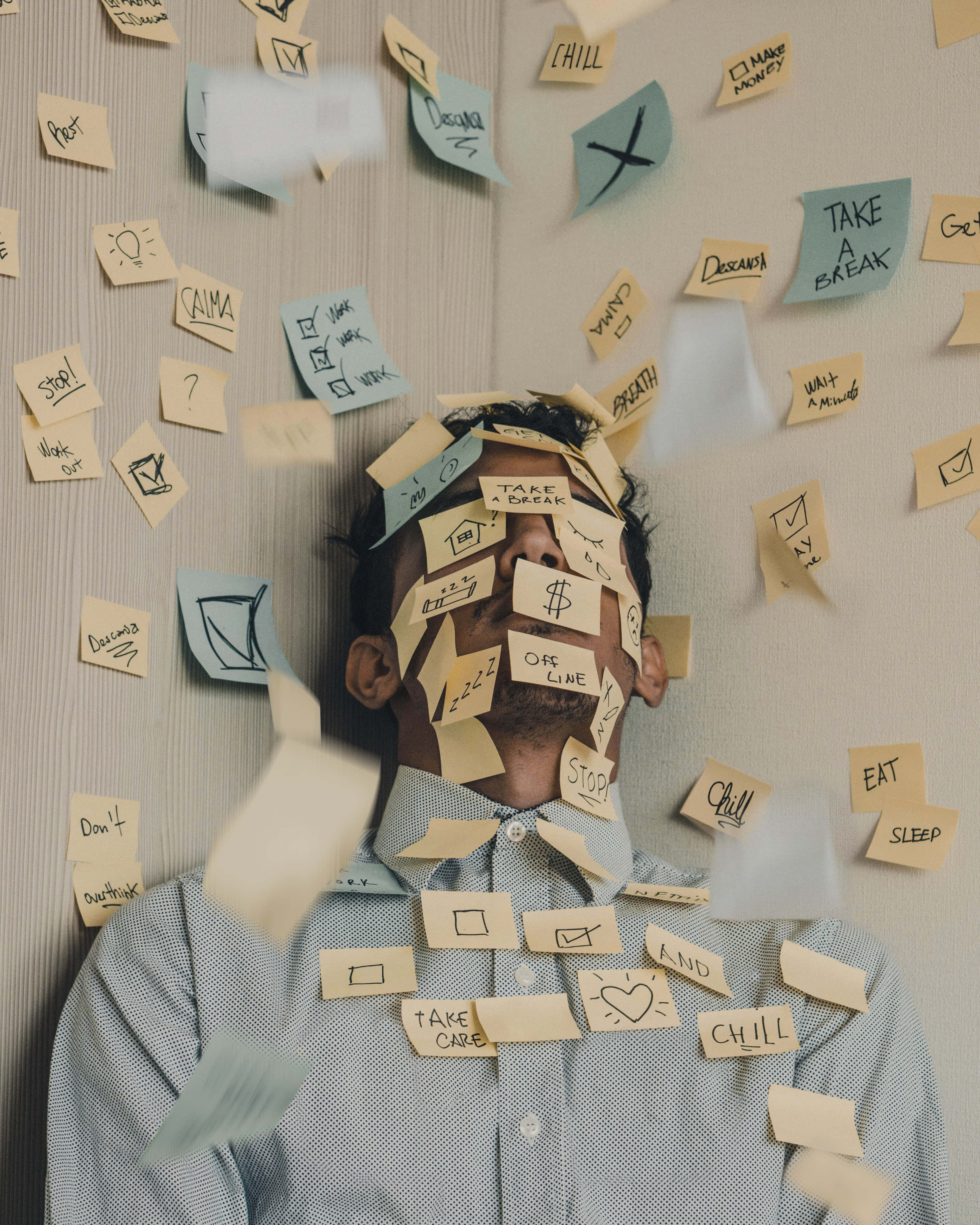 Stress 桌布 壁紙 — 一個男人被敦促休息和自我照顧的便利貼淹沒，覆蓋了他的臉和襯衫。