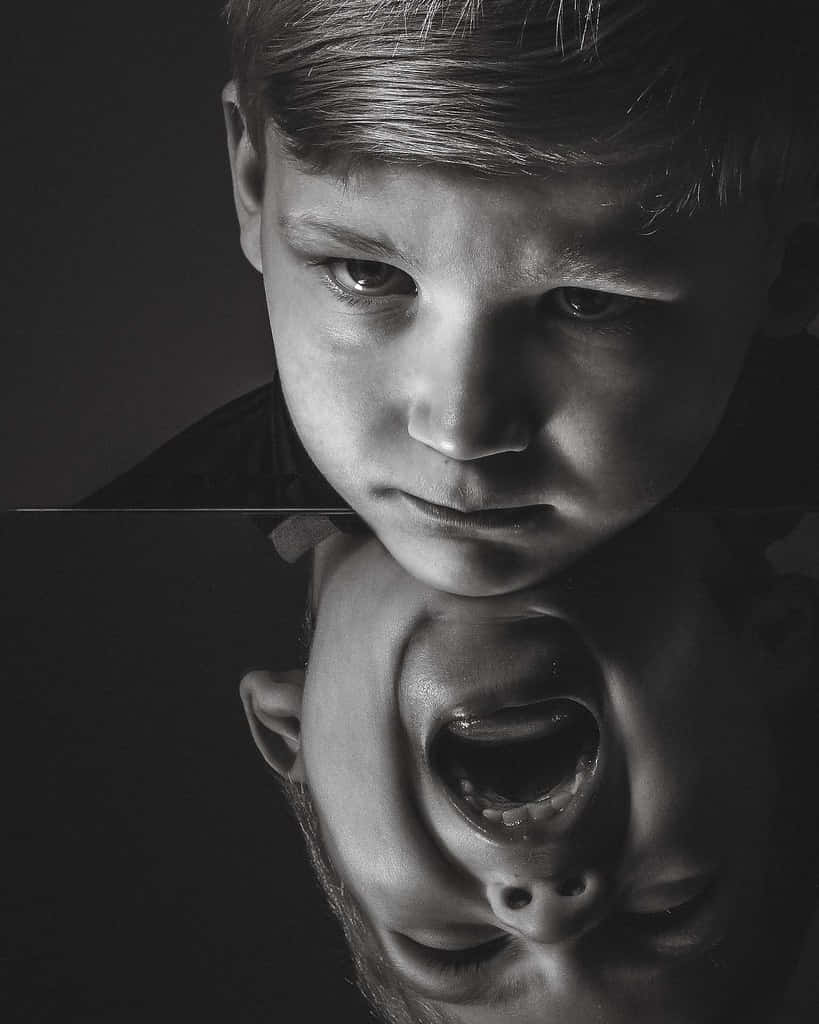 reflection 桌布 壁紙 — 一個男孩的黑白肖像，表情平靜，下方映照出一個扭曲尖叫的臉孔。