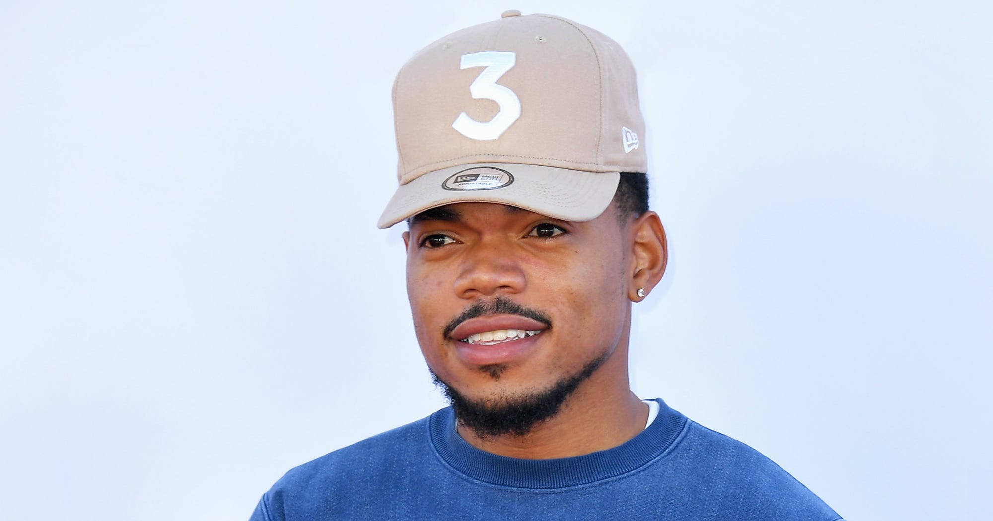 chance 桌布 壁紙 — 一個留山羊鬍和戴耳環的男人，戴著一頂米色帽子，上面有白色數字三，穿著藍色運動衫，背景是純色淺色。