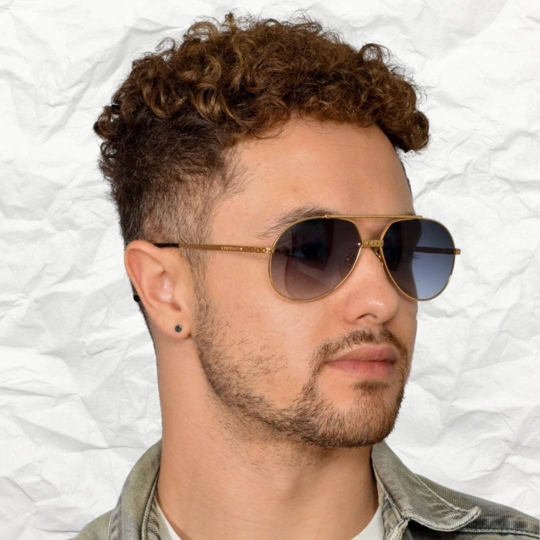 Sunglasses 桌布 壁紙 — 一個留著棕色捲髮、戴著飛行員太陽眼鏡的男人，在皺巴巴的白色紙張背景前擺姿勢。