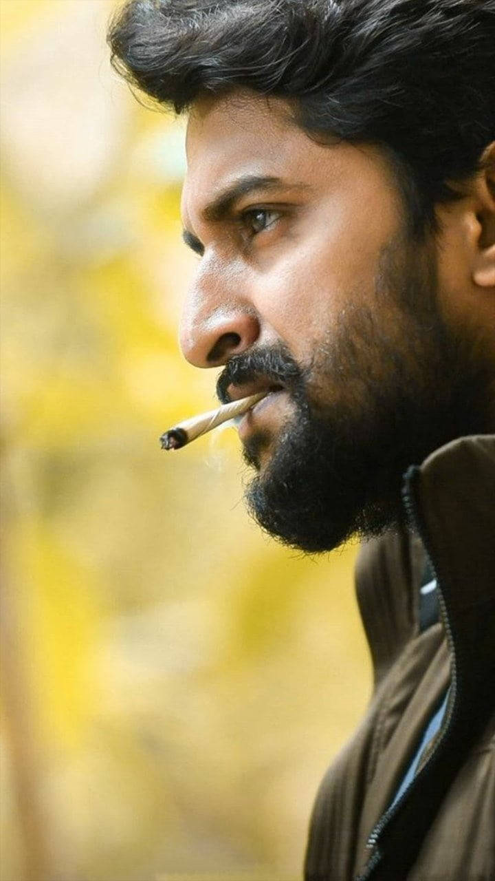 Indian 桌布 壁紙 — 一個留著深色鬍鬚的男人在柔和的黃色模糊背景前抽煙。