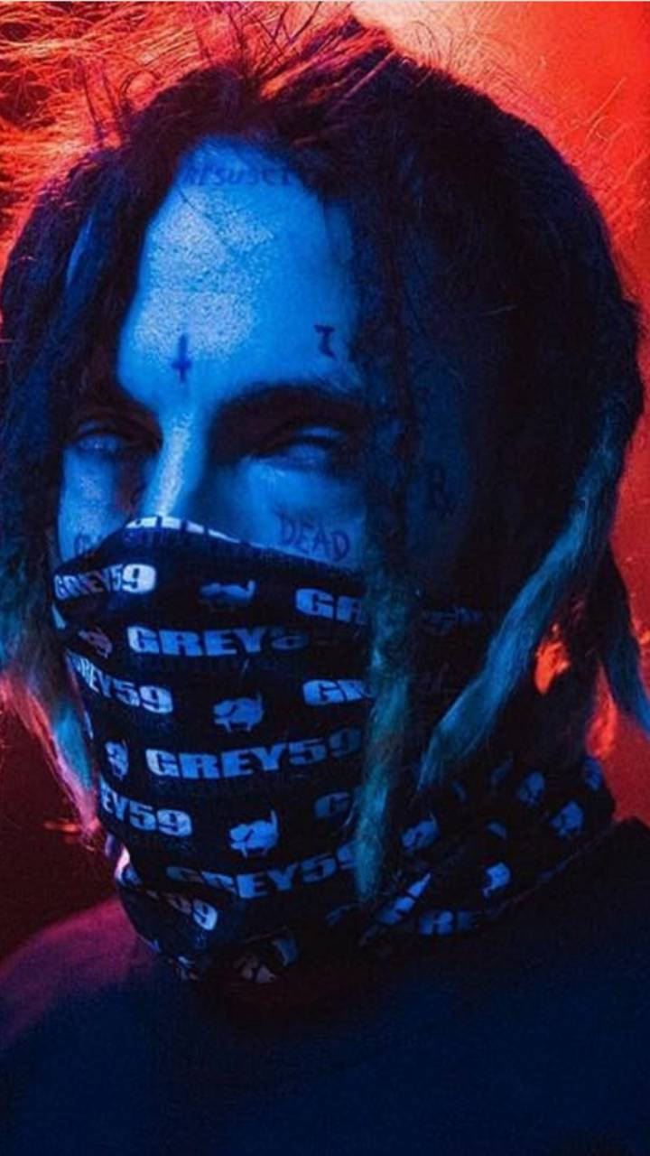 suicideboys 桌布 壁紙 — 一個留著辮子、戴著口罩的人，在強烈的藍色和紅色燈光下，臉上帶有塗鴉般的標記。