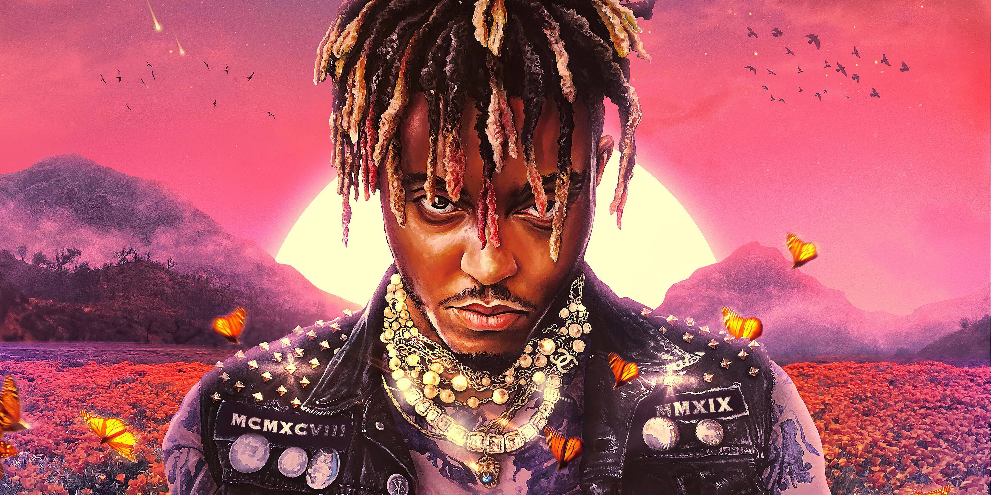 Juice Wrld Desktop 桌布 壁紙 — 一個留著辮子、戴著華麗珠寶的男人站在花田裡，背景是粉紅色的日落、蝴蝶和山脈。