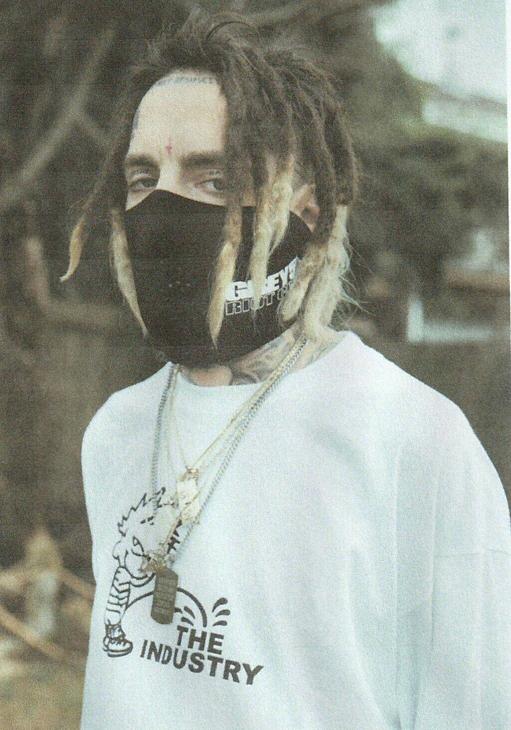 suicideboys 桌布 壁紙 — 一個留著辮子、戴著黑色口罩的人，在戶外穿著一件白色圖案連帽衫。