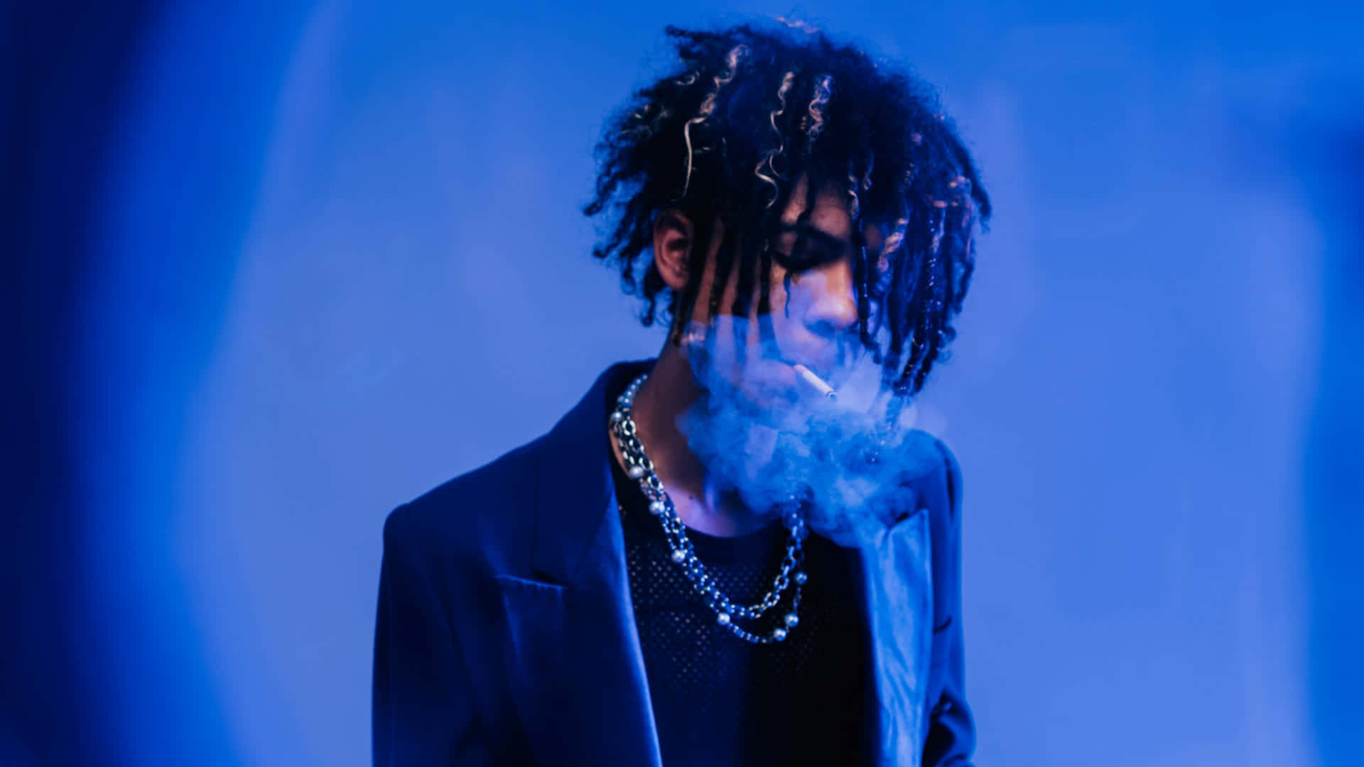Music 桌布 壁紙 — 一個留著辮子的人在模糊背景的冷藍色燈光下呼出煙霧。