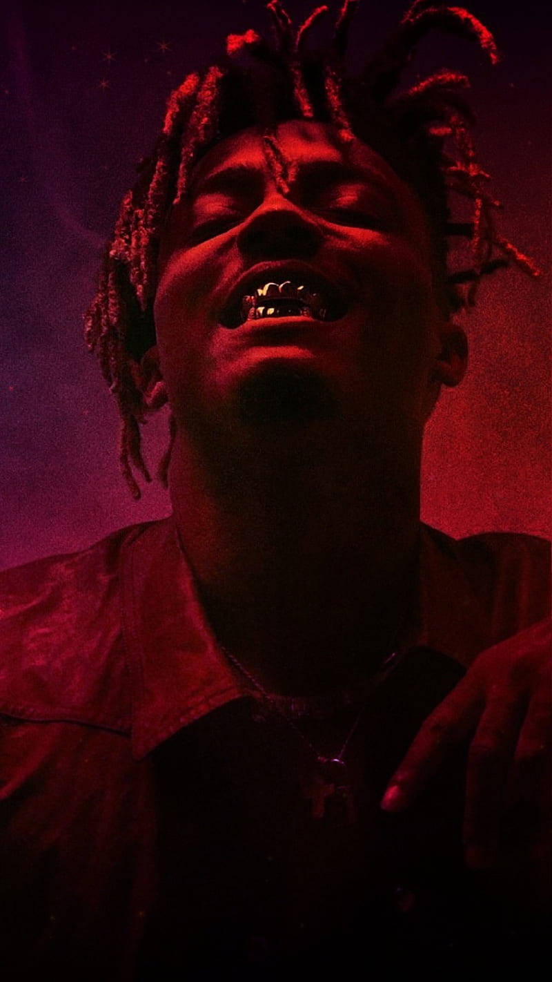 留著辮子頭、戴著金色牙套的人，在紅光下微笑。 — Juice Wrld 壁紙