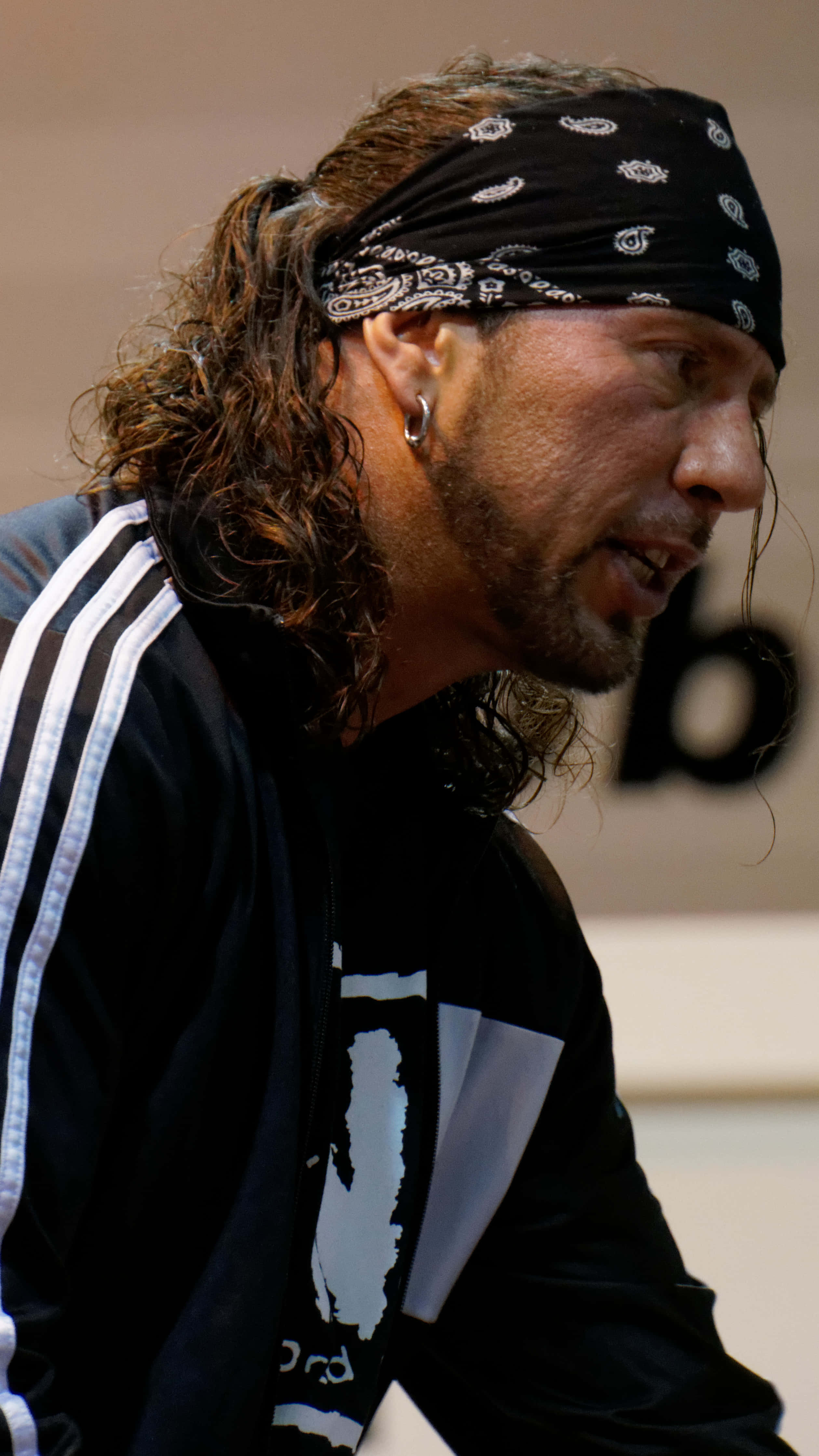 WWE 桌布 壁紙 — 一個留著長捲髮、戴黑色頭巾的男人，穿著黑色Adidas外套，專注地向前看。