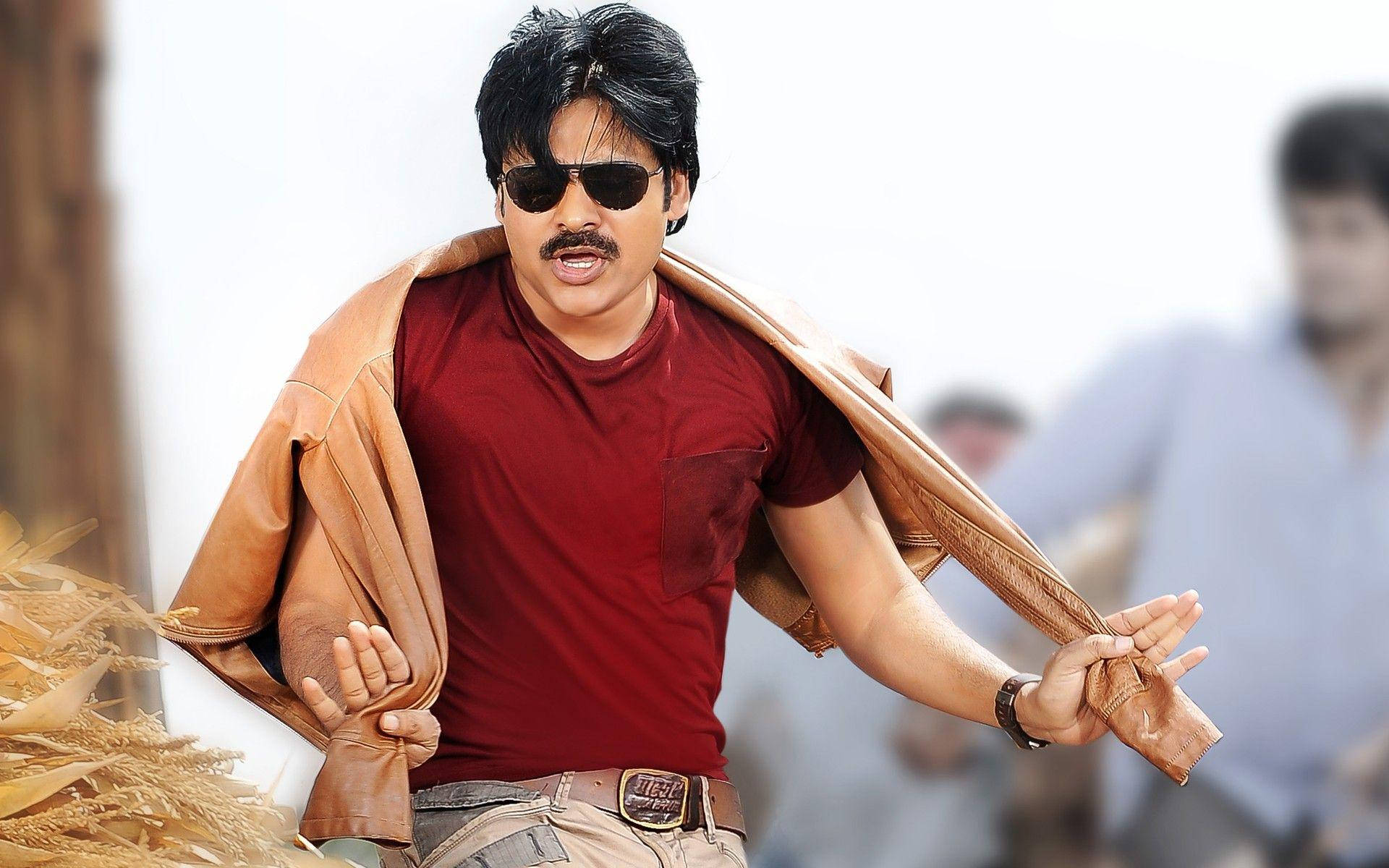 Pawan Kalyan 桌布 壁紙 — 一個留鬍子、戴太陽眼鏡的男人，肩上披著一件棕褐色外套，走過一片金黃色的麥田。