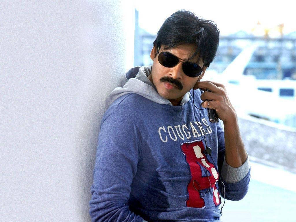 Pawan Kalyan 桌布 壁紙 — 一個留鬍子、戴太陽眼鏡的男人靠著白色牆壁，戴著耳機聽音樂。
