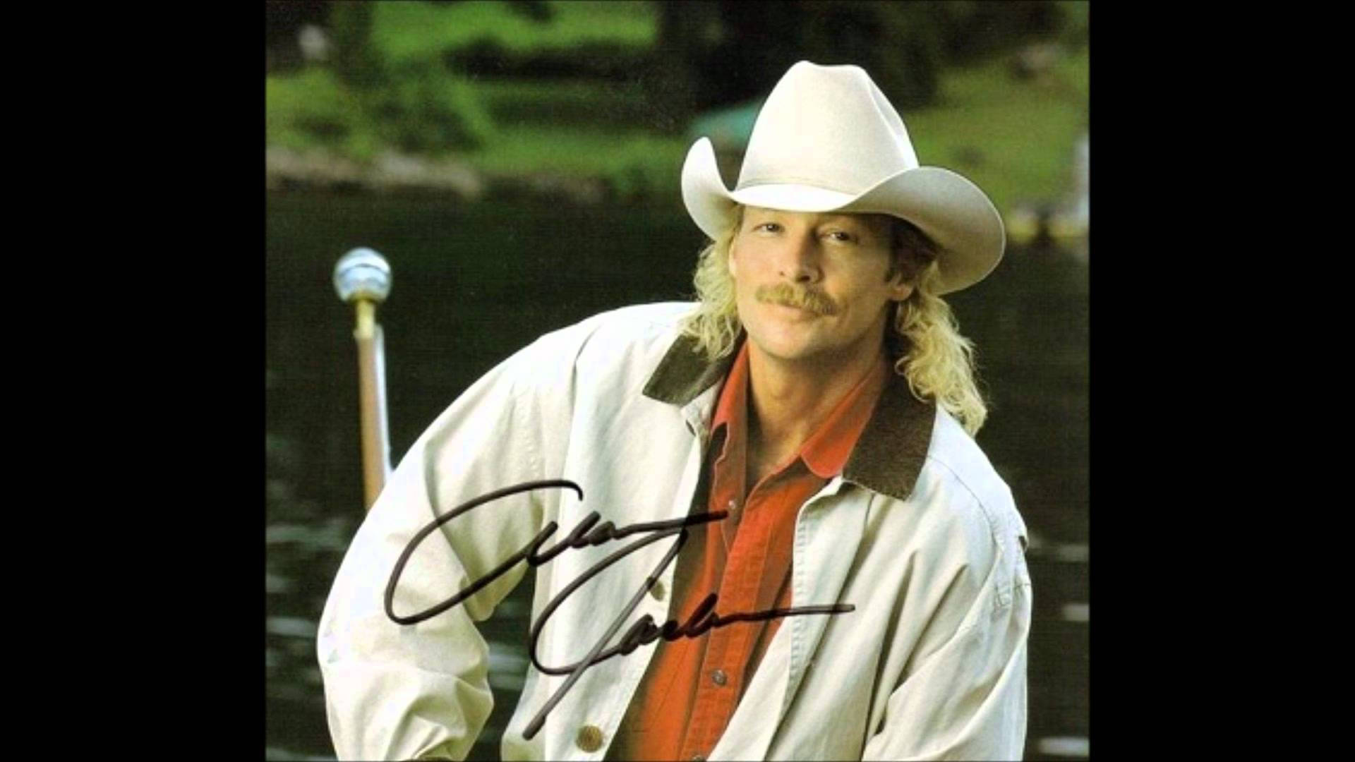 Alan Jackson 桌布 壁紙 — 一個留鬍子、戴牛仔帽的男人站在水邊，手持棒球棍，前景有他的簽名。