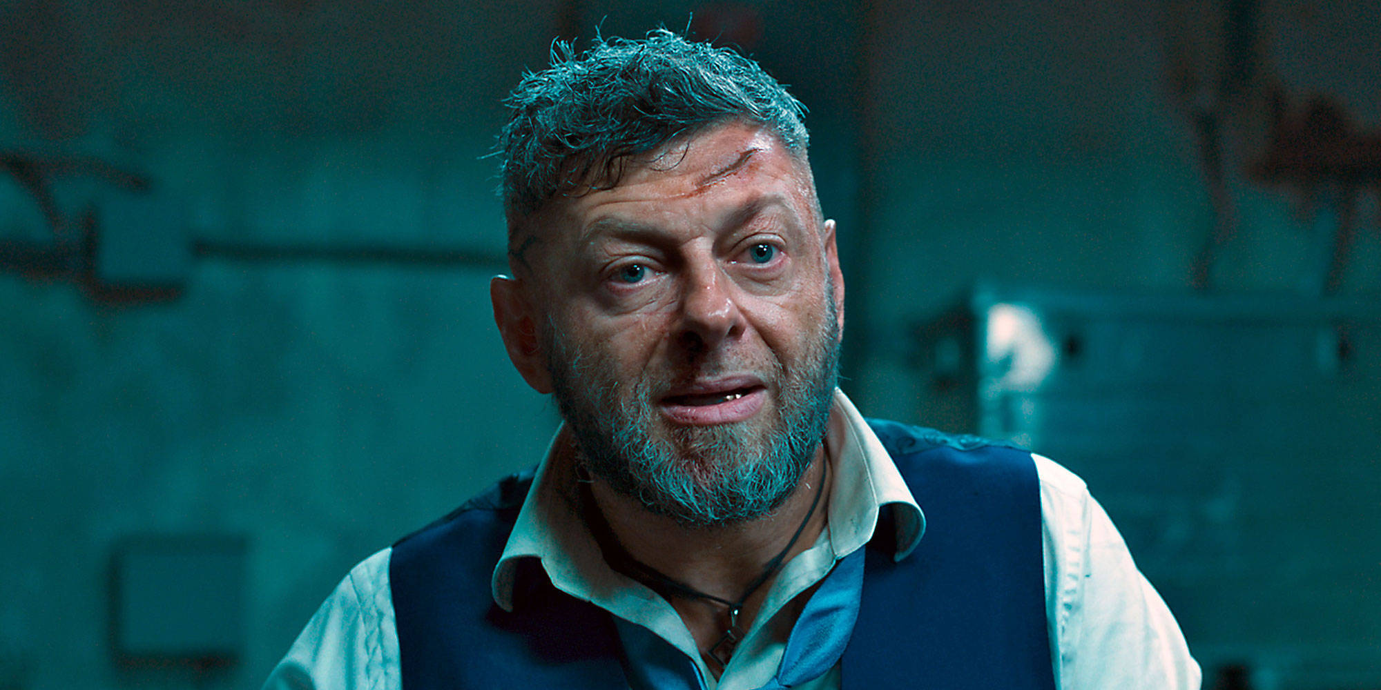 actor 桌布 壁紙 — 一個留鬍子、臉上有瘀傷的男人在昏暗的藍綠色房間裡專注地凝視。