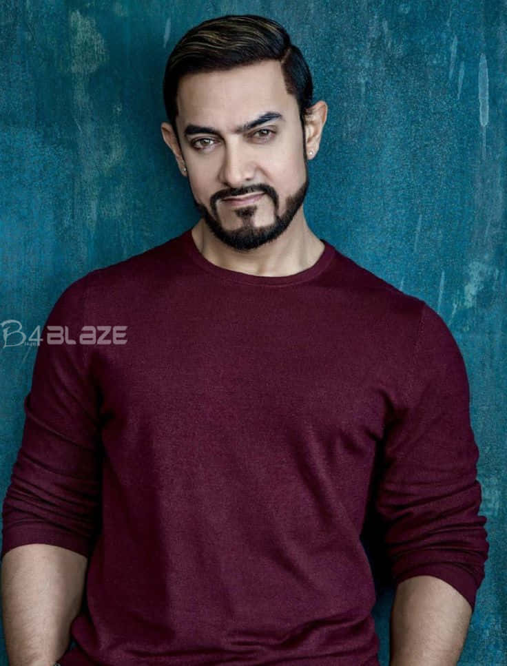 Aamir Khan 桌布 壁紙 — 一個留鬍子、頭髮有造型的男人，穿著栗色毛衣，背景是帶紋理的青綠色牆壁。