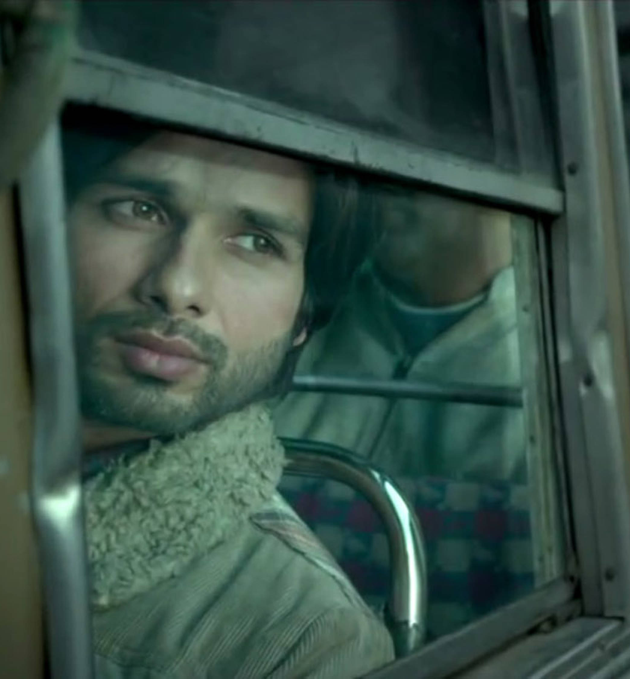 Shahid Kapoor 桌布 壁紙 — 一個留鬍子的男人，透過金屬欄杆和圖案座椅框住的陳舊火車車窗，若有所思地凝視窗外。