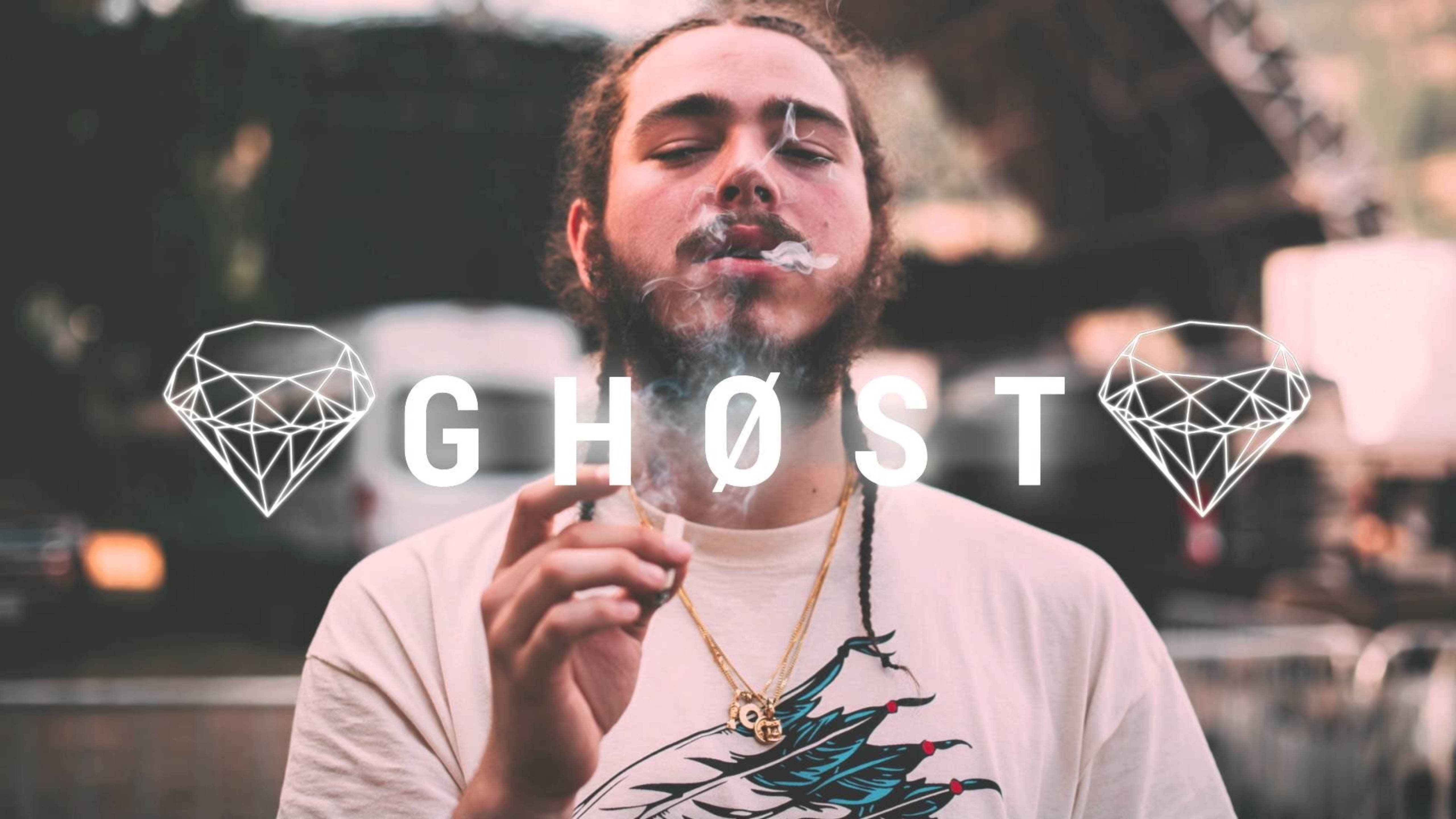 Post Malone 桌布 壁紙 — 一個留鬍子的男人呼出煙霧，同時拿著一支帶有 'GHOST' 文字和鑽石圖案覆蓋的電子煙筆。
