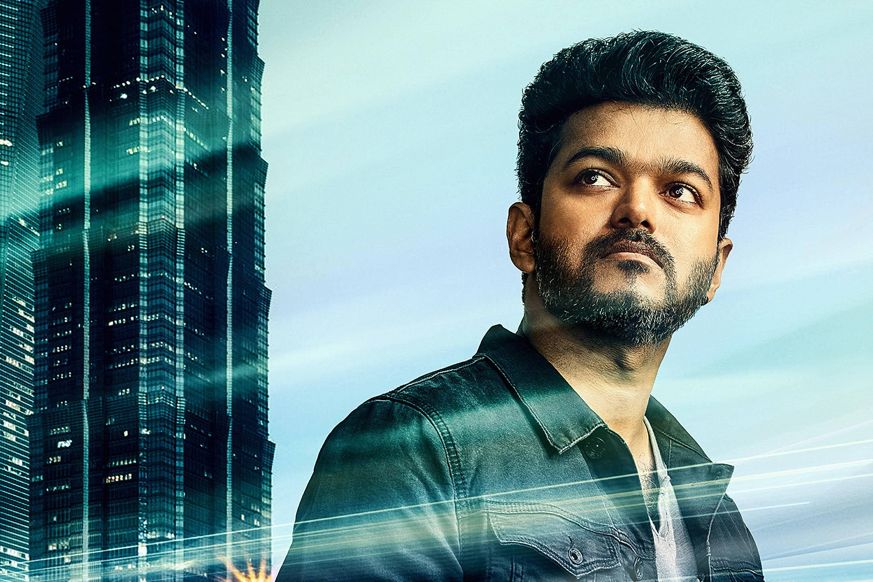 vijay HD 桌布 壁紙 — 一個留鬍子的男人在明亮的天空和光線條紋下，抬頭仰望旁邊高聳的玻璃摩天大樓。