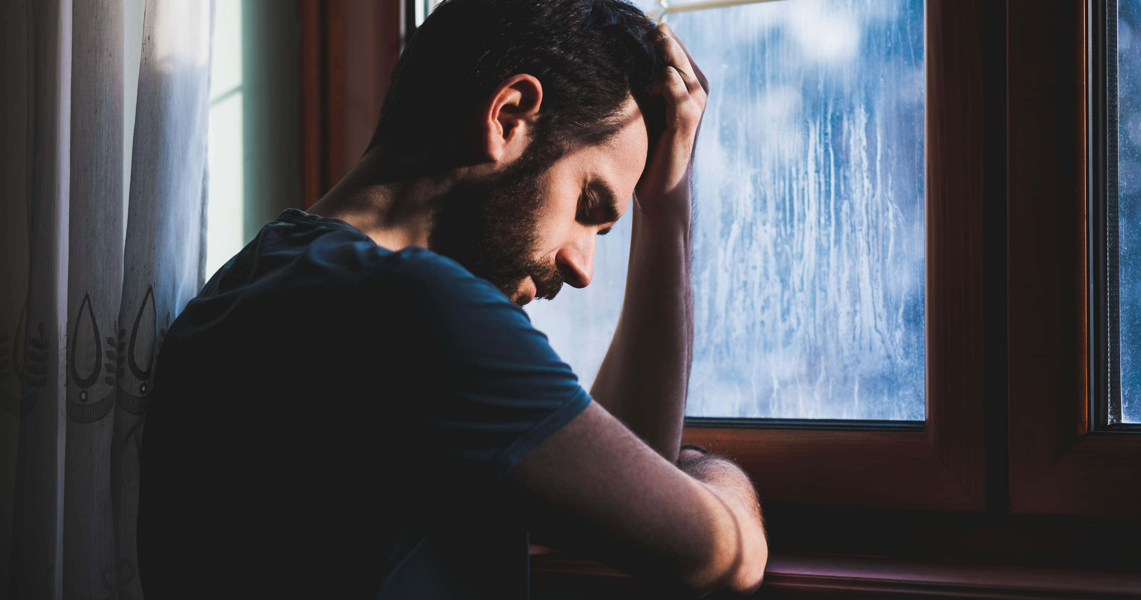 Depressed 桌布 壁紙 — 一個留鬍子的男人坐在雨痕斑斑的窗邊，低著頭，手放在頭上，陷入無聲的絕望。