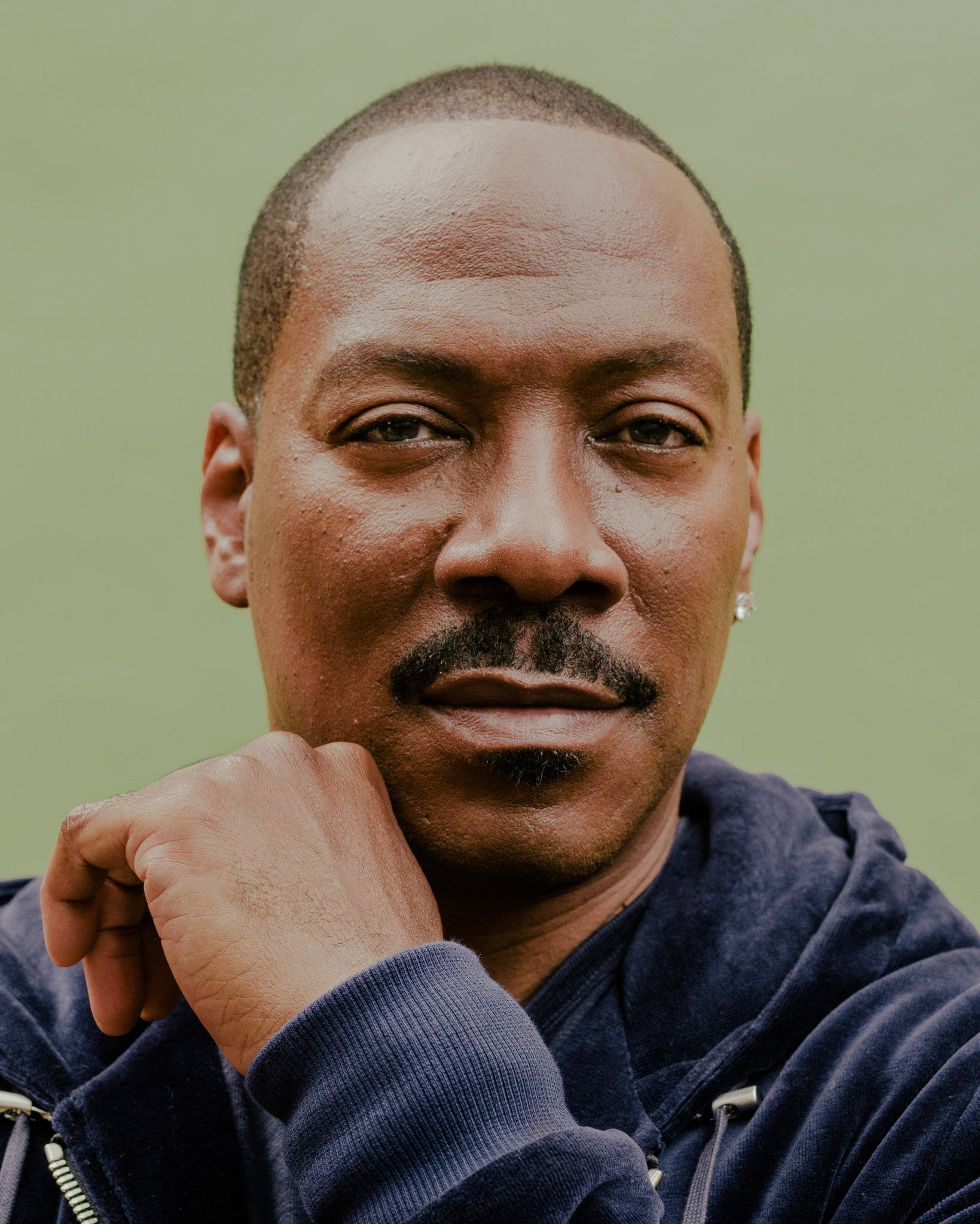 eddie murphy 桌布 壁紙 — 一個留鬍子的男人特寫肖像，他將下巴托在手上，背景是柔和的綠色。