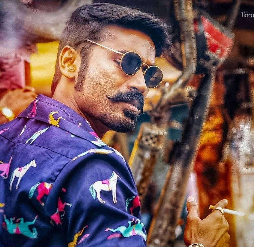 Bollywood HD 桌布 壁紙 — 一個留鬍鬚、戴圓形太陽眼鏡的男人，穿著一件帶有彩色馬圖案的鮮紫色襯衫，正在抽煙。