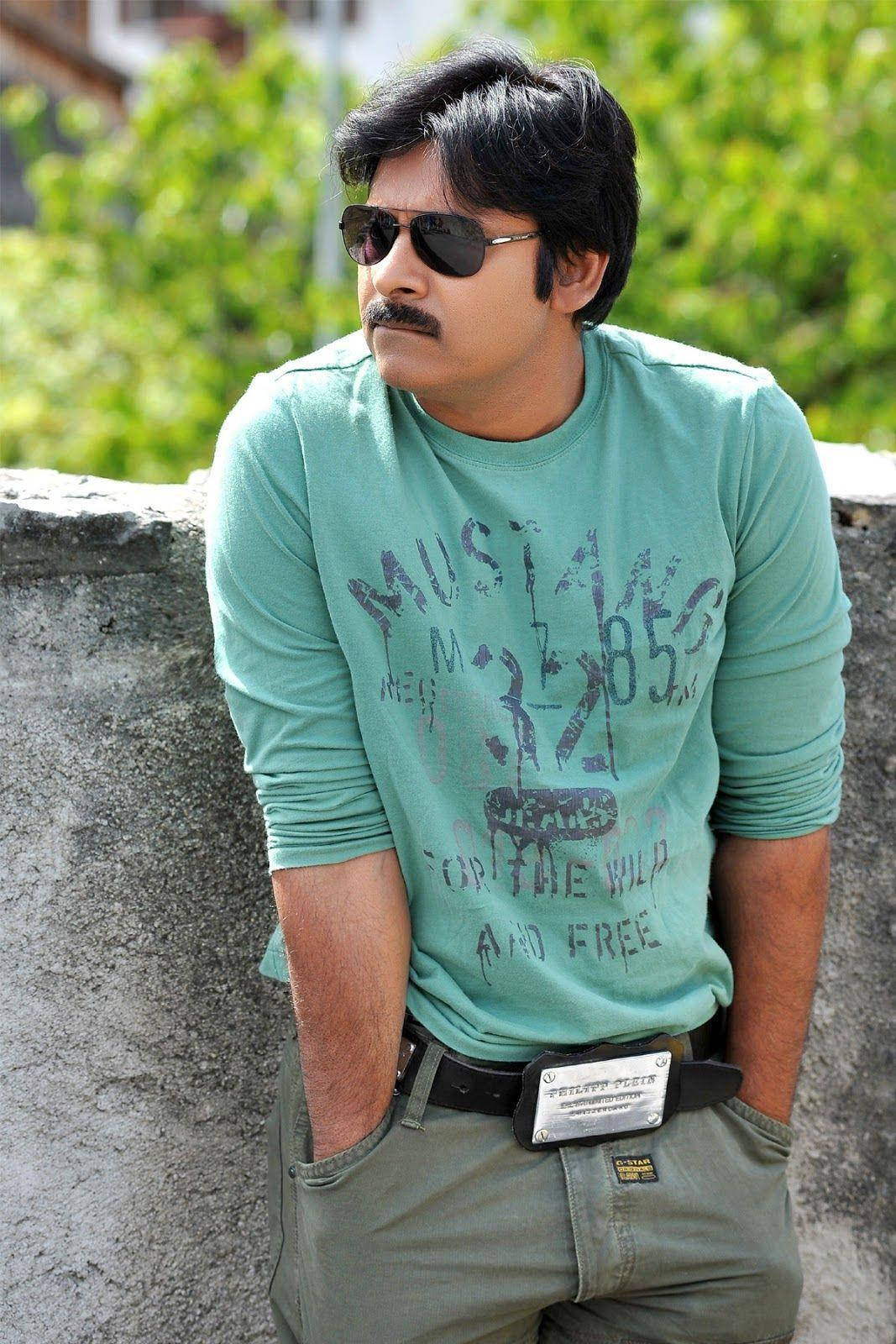Pawan Kalyan 桌布 壁紙 — 一個留鬍鬚、戴太陽眼鏡的男人，在明亮日光下穿著綠色T恤靠在石牆上。
