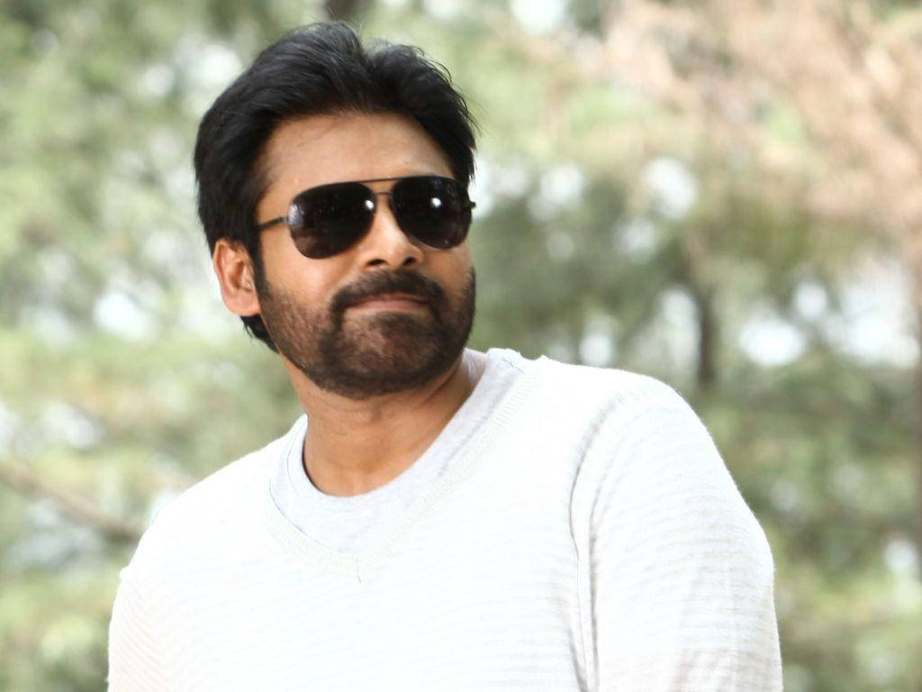 Pawan Kalyan 桌布 壁紙 — 一個留鬍鬚、戴太陽眼鏡的男人，穿著白色毛衣，背景是模糊的綠色樹木。
