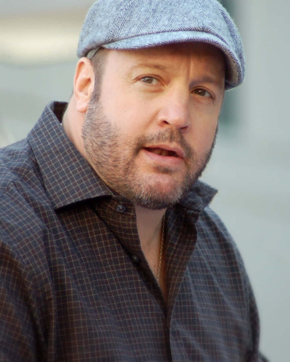 Kevin James 桌布 壁紙 — 一個留鬍鬚、戴灰色平頂帽的男人，穿著格紋襯衫，直視鏡頭。