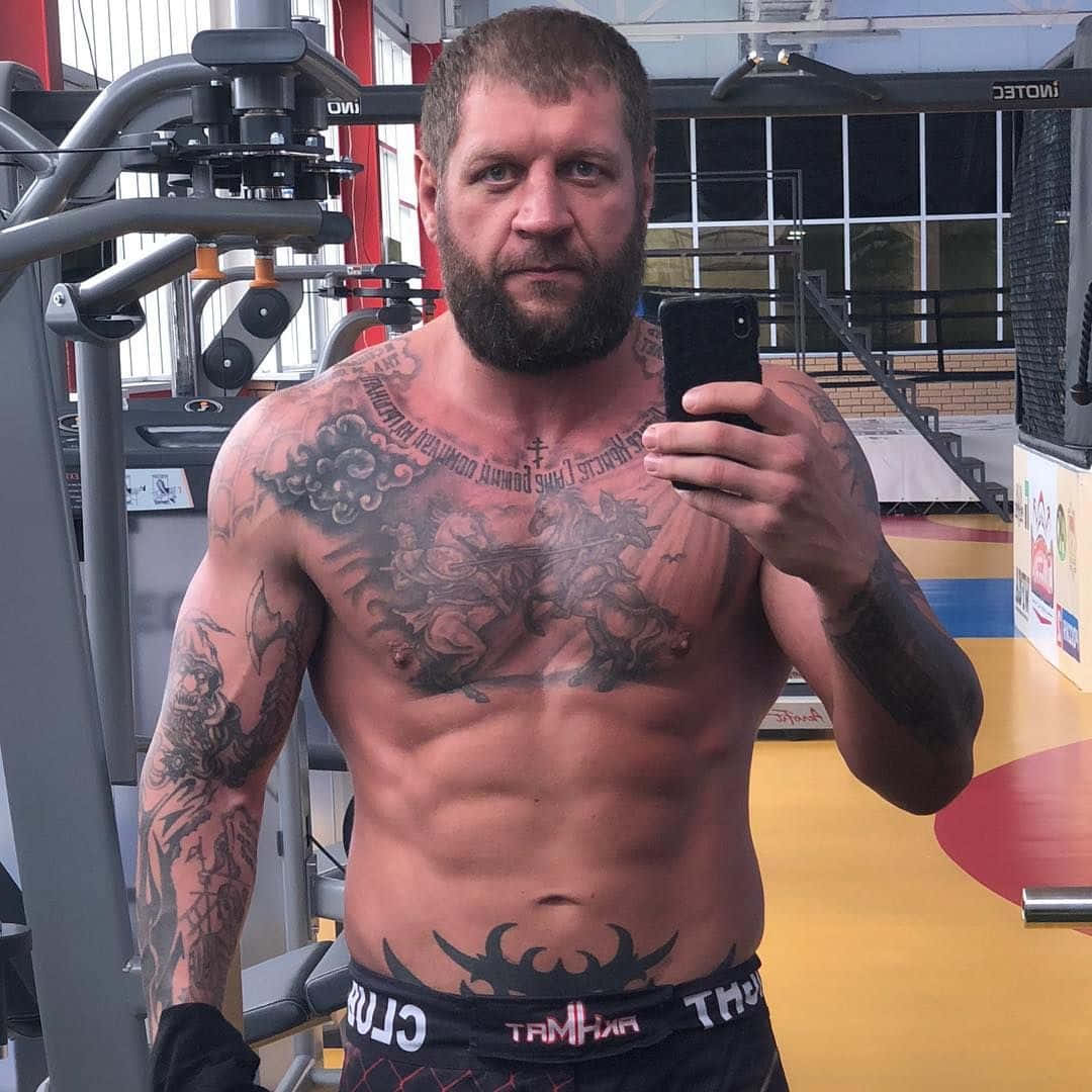 MMA 桌布 壁紙 — 一個留鬍鬚、滿身刺青的肌肉男在健身房穿著黑色短褲對著鏡子自拍。