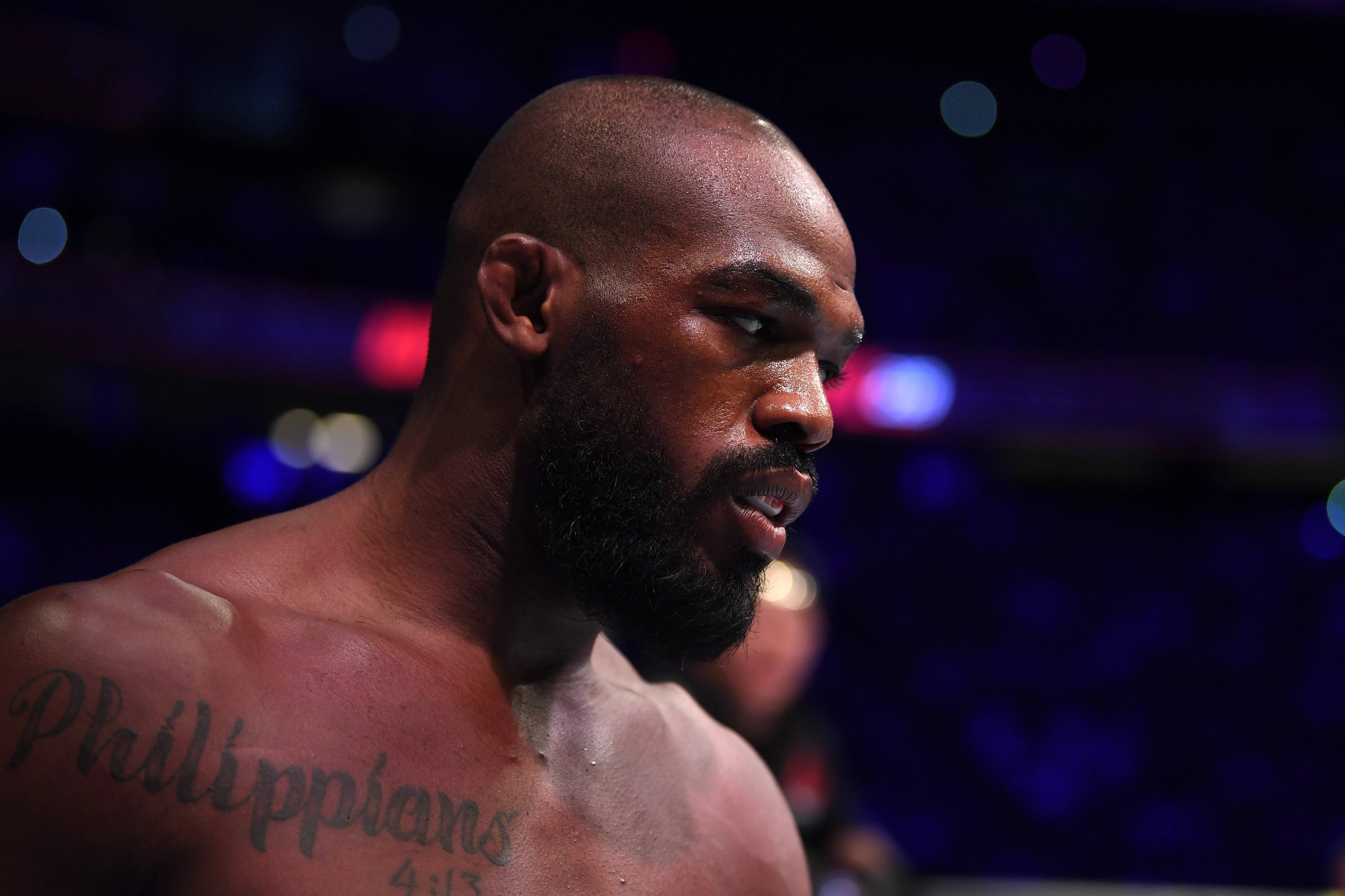 UFC 桌布 壁紙 — 一個留鬍鬚、紋有「腓立比書 4:13」的專注戰士，在昏暗的競技場中，模糊的彩色燈光下凝視著。