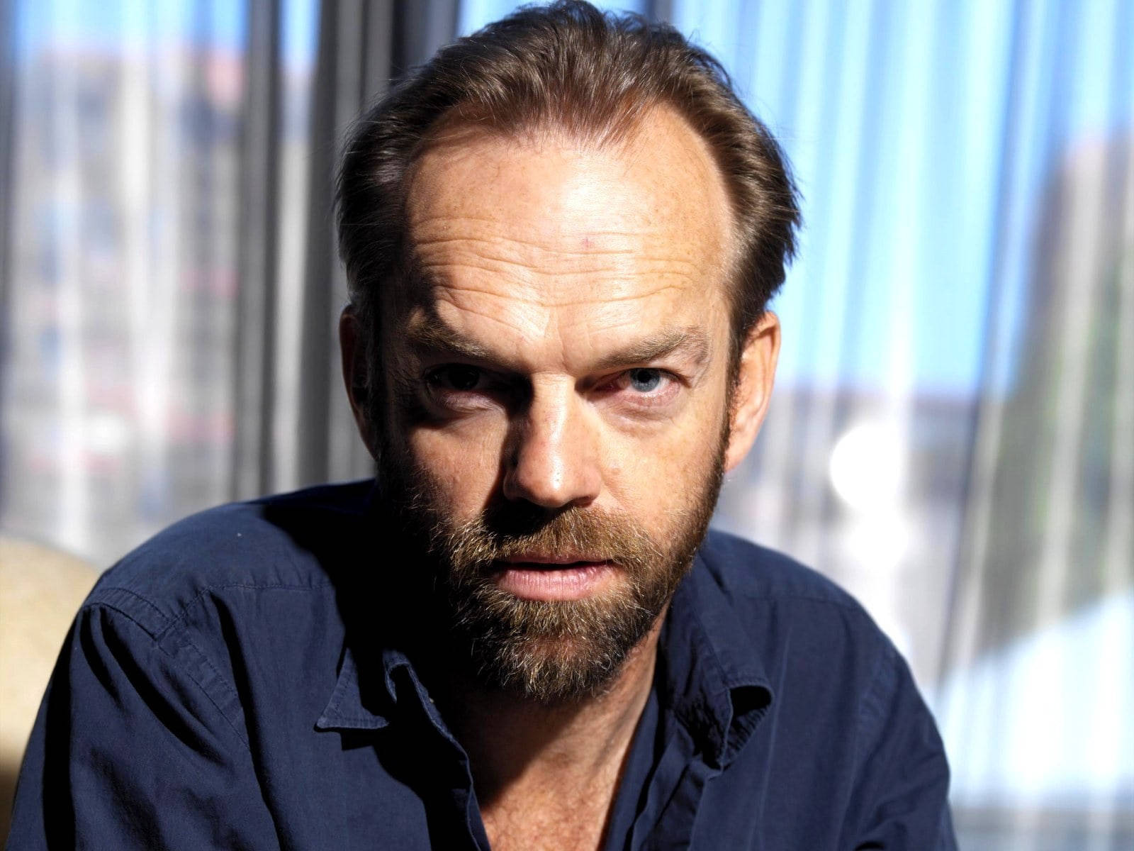 actor 桌布 壁紙 — 一個留鬍鬚的男人，在陽光充足的房間裡，隔著薄窗簾直視鏡頭。
