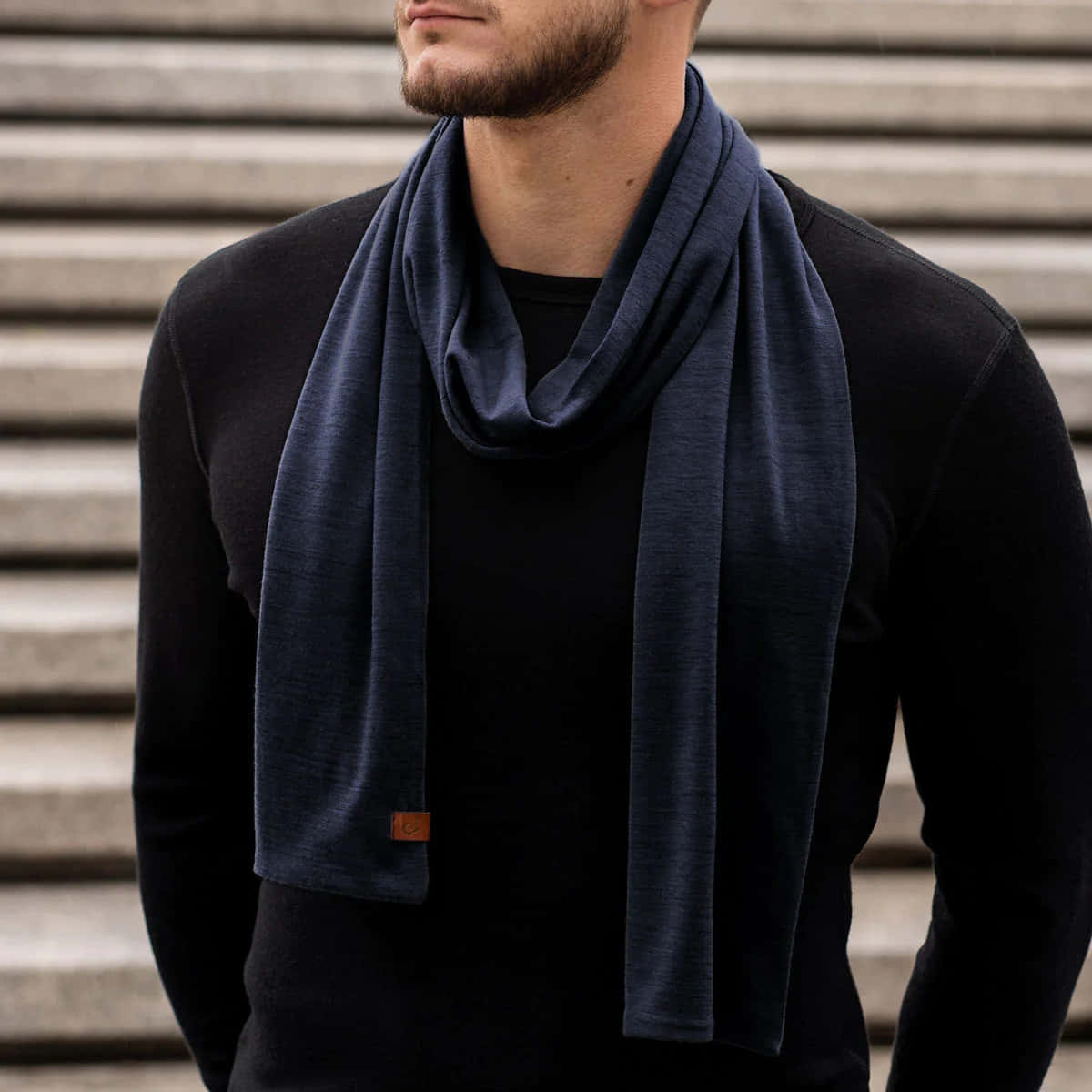 Navy Blue Scarf 桌布 壁紙 — 一個留鬍鬚的男人，戴著海軍藍圍巾和黑色毛衣，背景是灰色波紋牆。