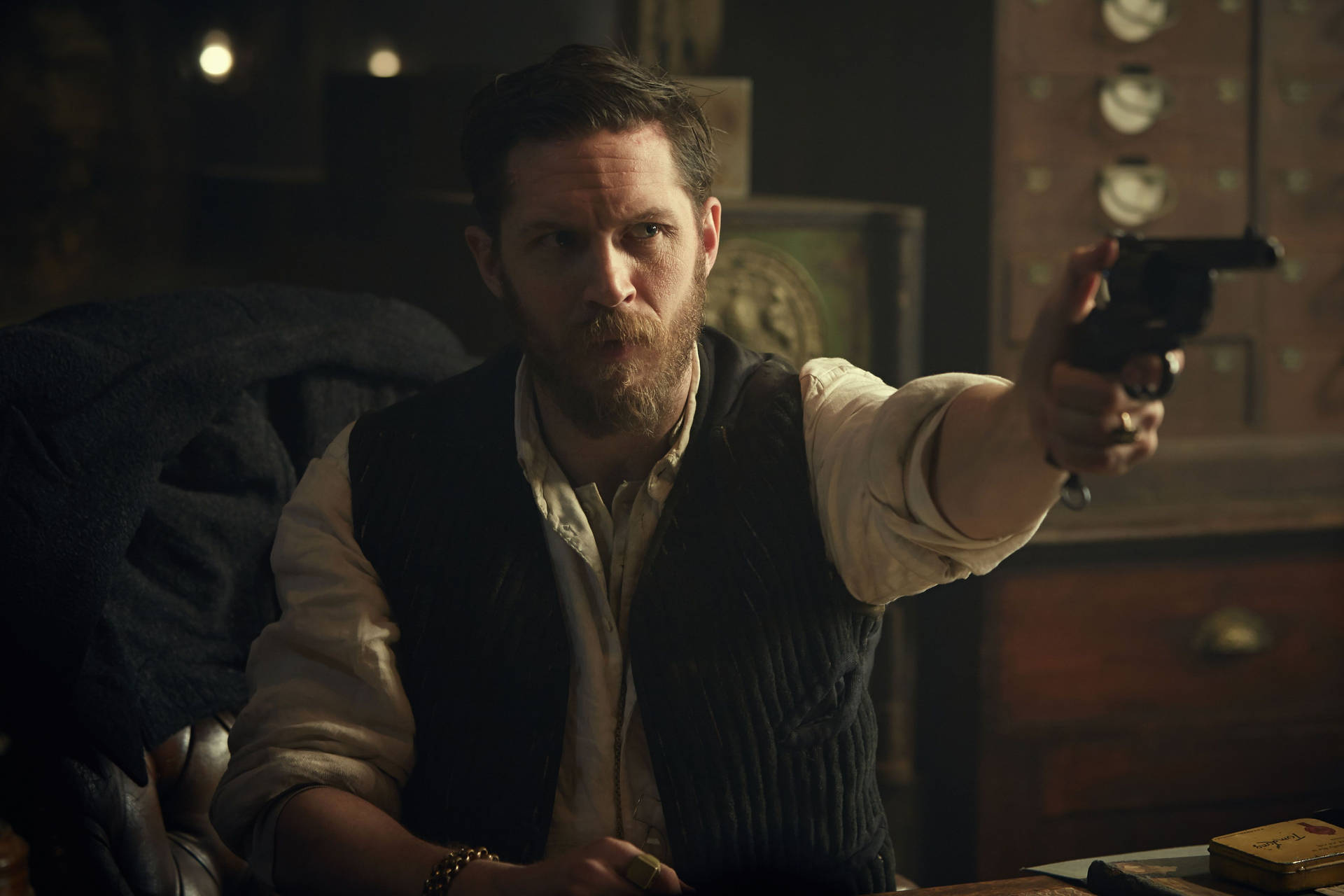 留鬍鬚的男人在昏暗房間中指著左輪手槍 — Peaky Blinders 壁紙