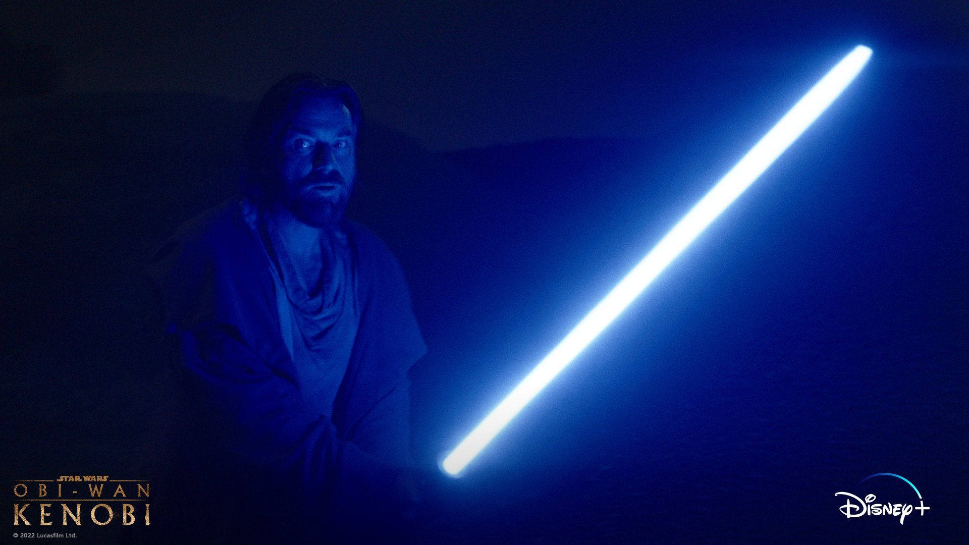 Kenobi 桌布 壁紙 — 一個留鬍鬚的男人在黑暗環境中手持發光的藍色光劍，向陰影背景投射出明亮的光束。