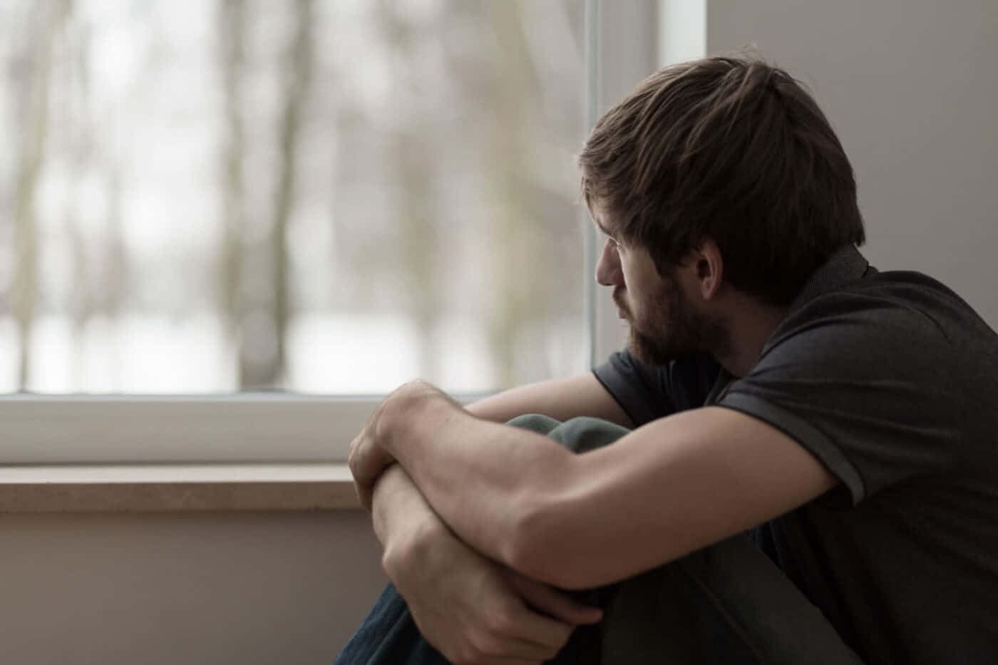 Depressed 桌布 壁紙 — 一個留鬍鬚的男人彎腰坐在窗邊，凝視著雪景，陷入沉思。
