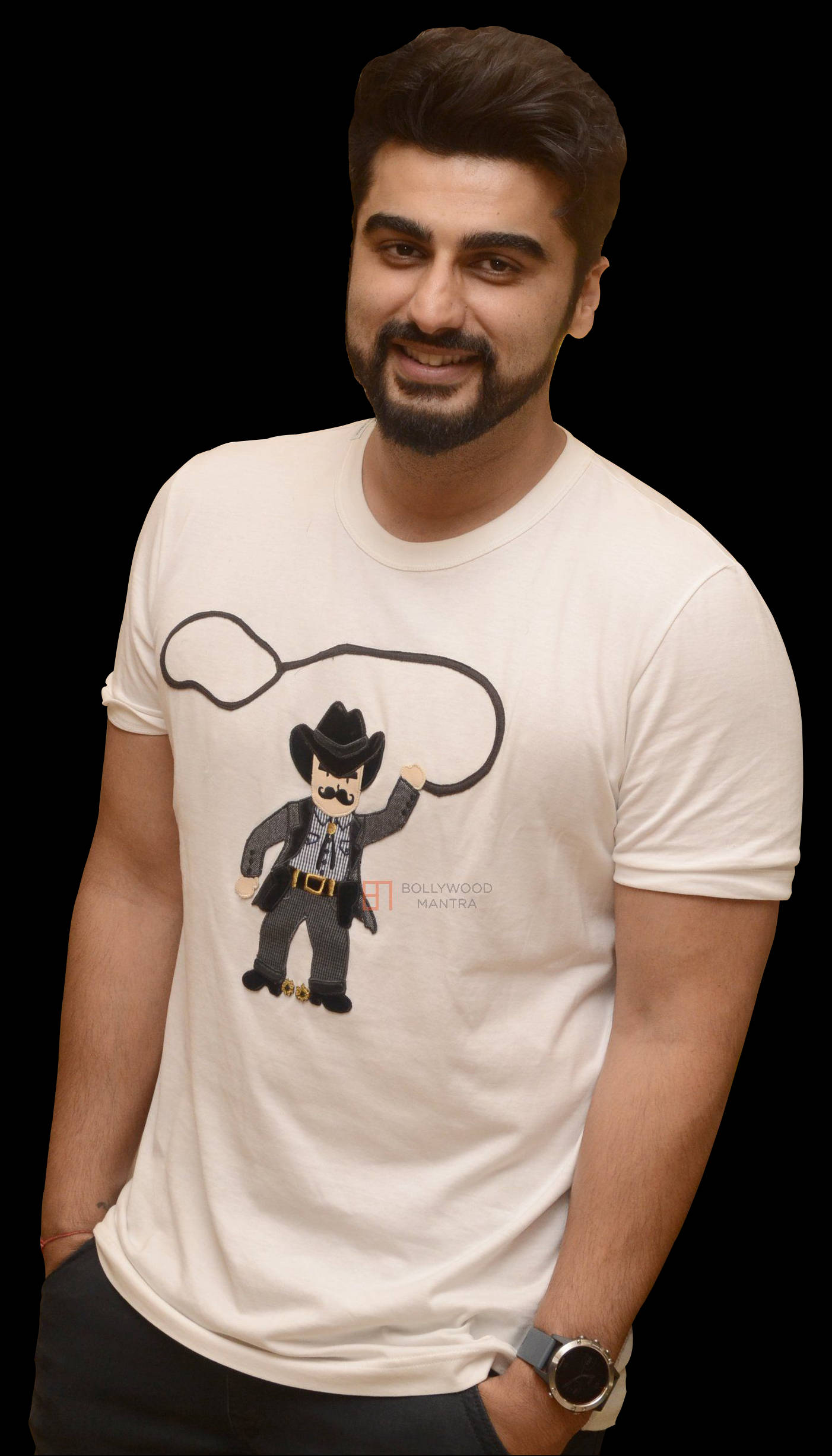 Arjun Kapoor 桌布 壁紙 — 一個留鬍鬚的男人微笑著，身穿印有卡通牛仔圖案的白色T恤，背景為黑色。
